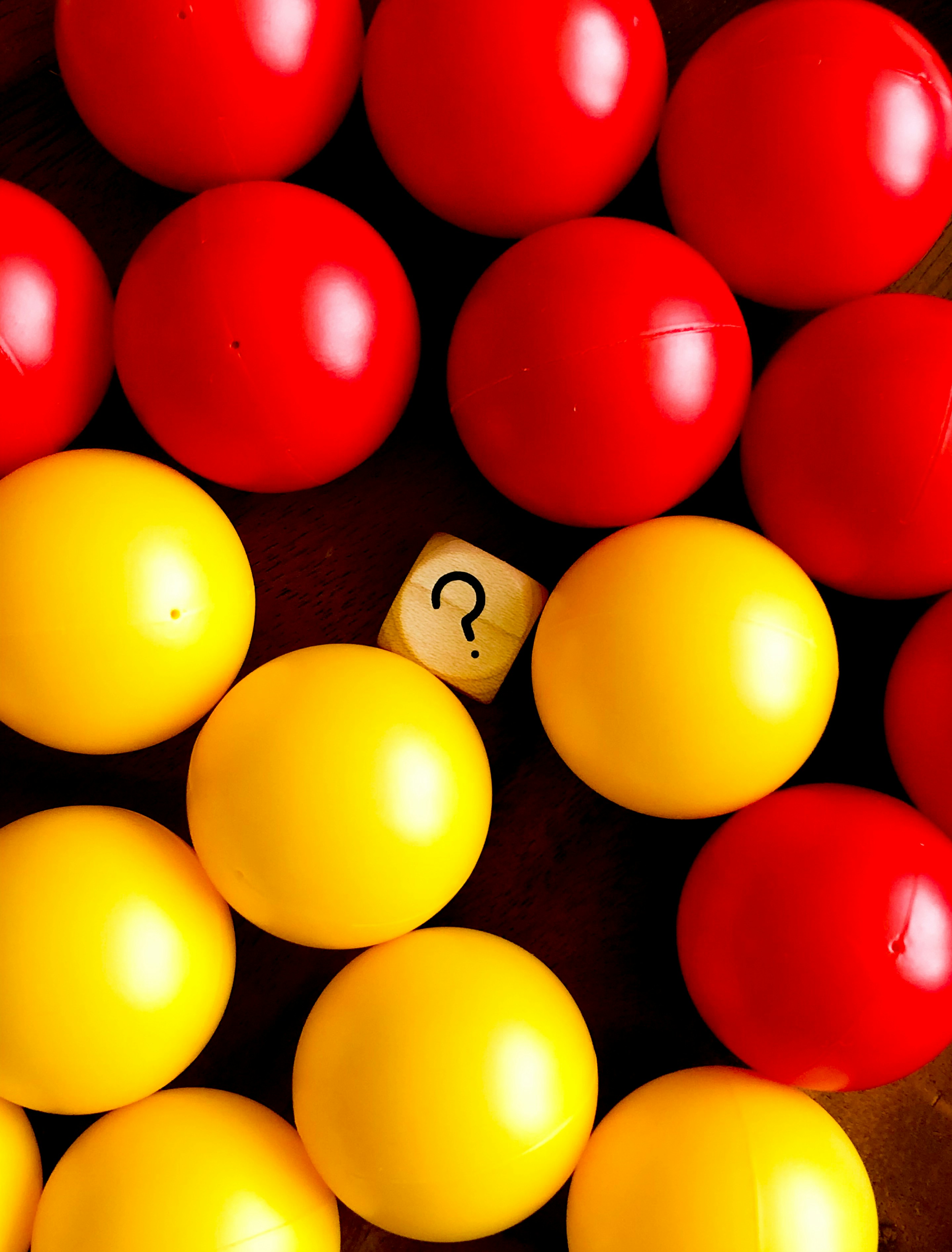 Colorful red and yellow balls surrounding a wooden cube with a question mark representing interview questions
