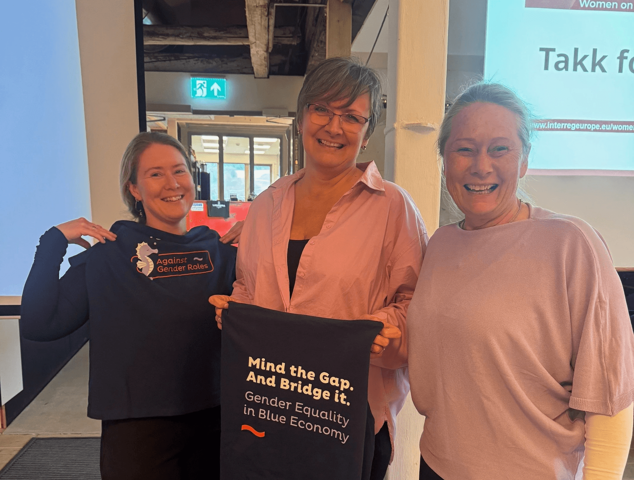 A person wearing a virtual reality headset stands in front of multiple screens, engaged in a digital experience.