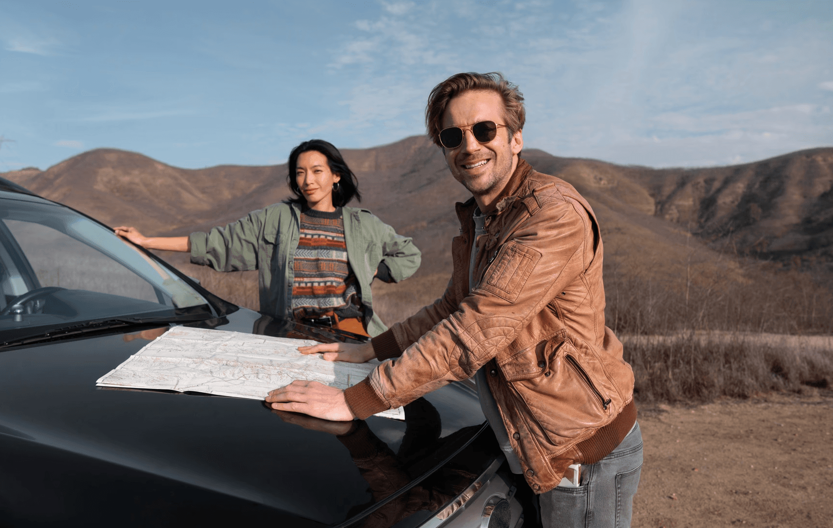 Couple reading a map on a car in the mountains.