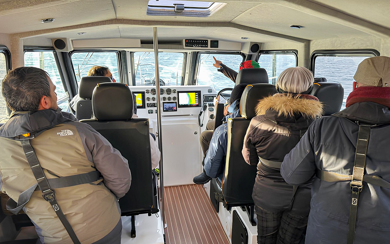 Tourists inside a boat during a whale watching tour from Tromso, viewing the sea through windows.