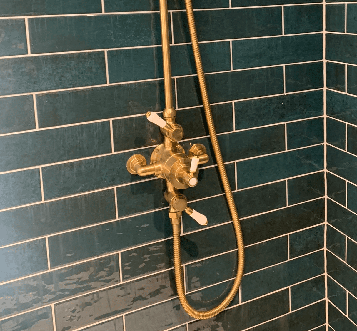 Brass shower fittings on green metro tiled shower enclosure