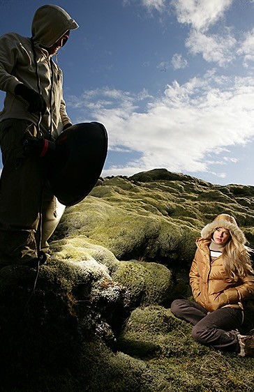 Crew member with reflector beside a seated subject outdoors