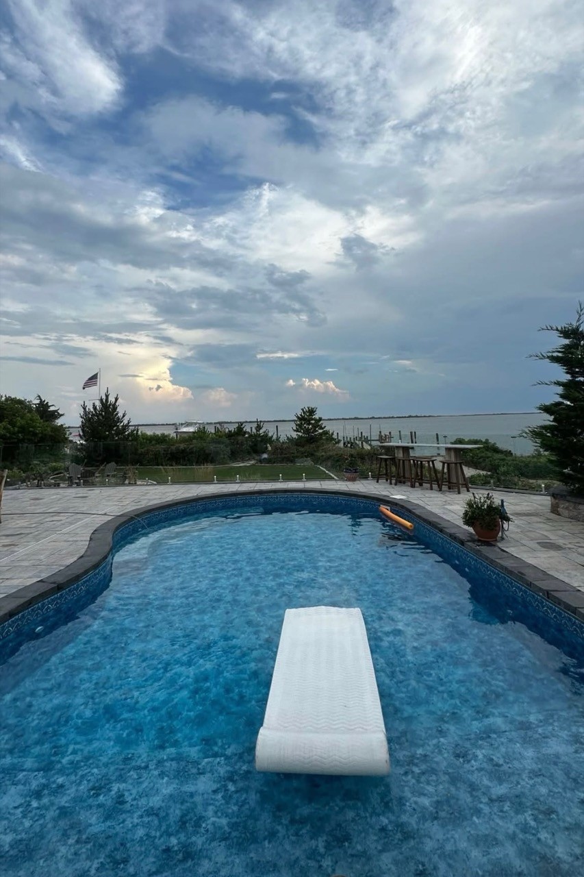 Freeform in-ground pool with paver deck by CMC Masonry on Long Island
