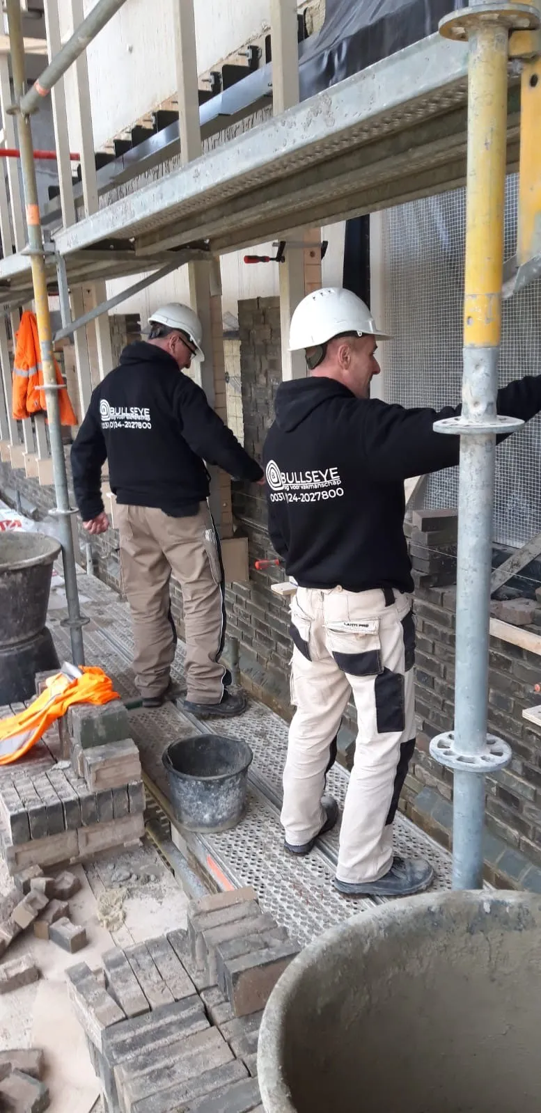 man in green and black plaid long sleeve shirt holding red and black cordless hand drill