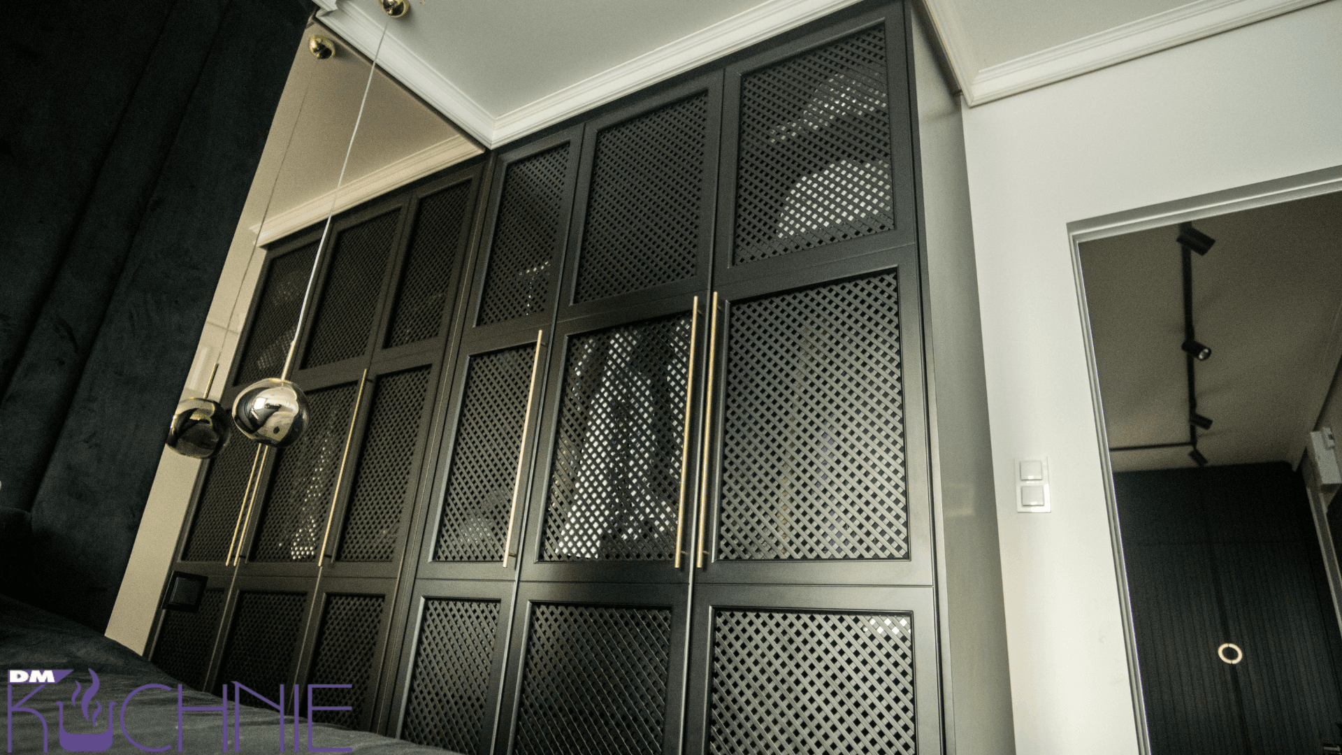 Meble na wymiar w Warszawie – czarna zabudowa z perforowanymi frontami i złotymi uchwytami