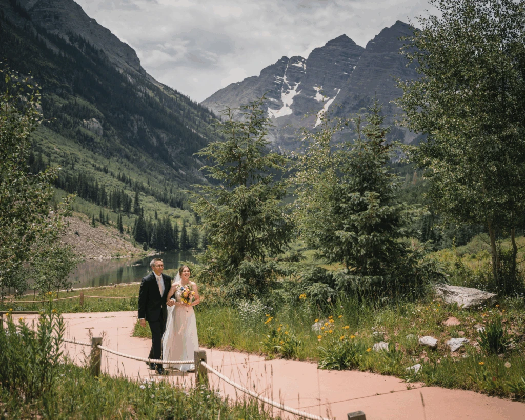 Newlyweds walking along a path through a mountain valley