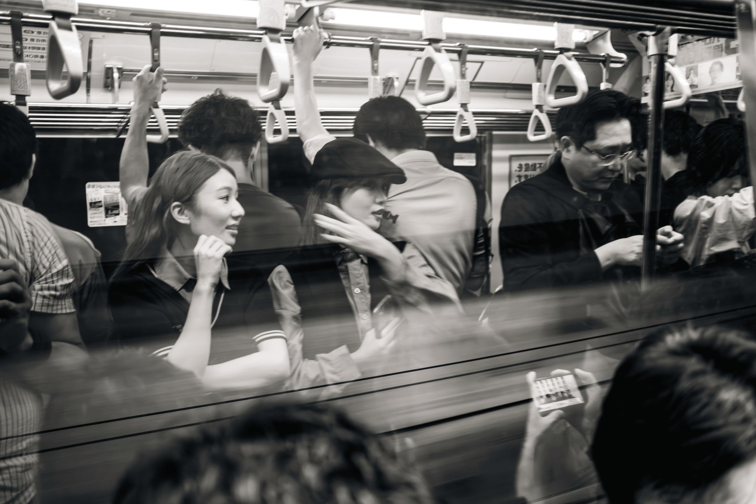 Black and white photograph of commuters packed inside a train during busy rush hour.