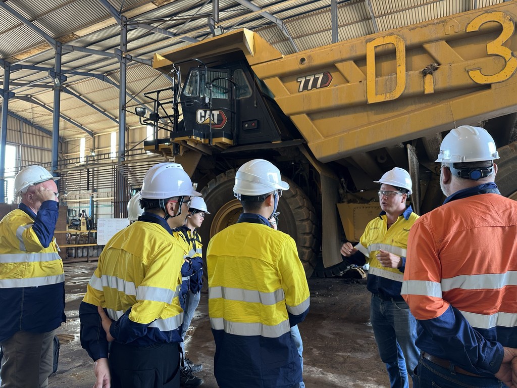 Akaliko workers discuss heavy equipment aftermarket parts for a large Cat truck.