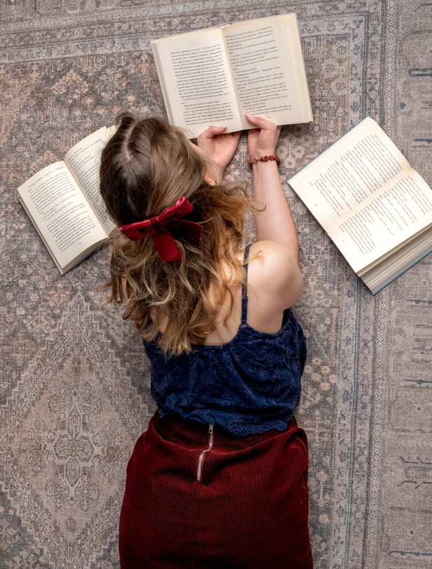 A földön fekve egy lány könyvet olvas.