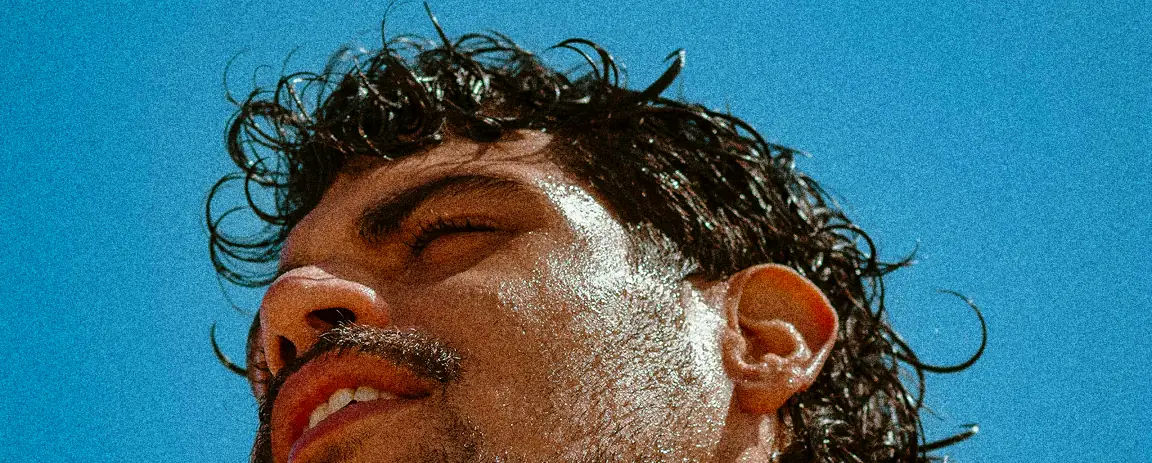 Warm-toned close-up portrait with sweat droplets capturing the high-energy mood of the brand.