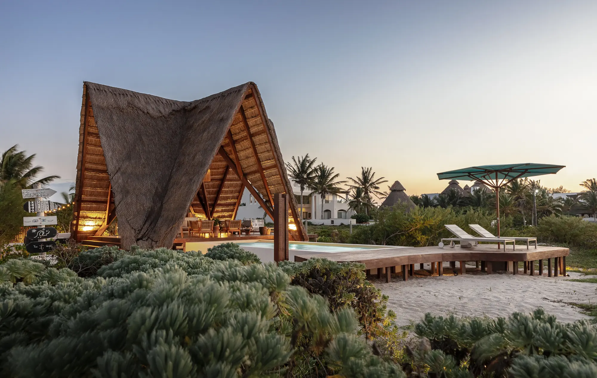 Tulum 21 - Vista hacia palapa y piscina, desde la playa con plantas en primer plano