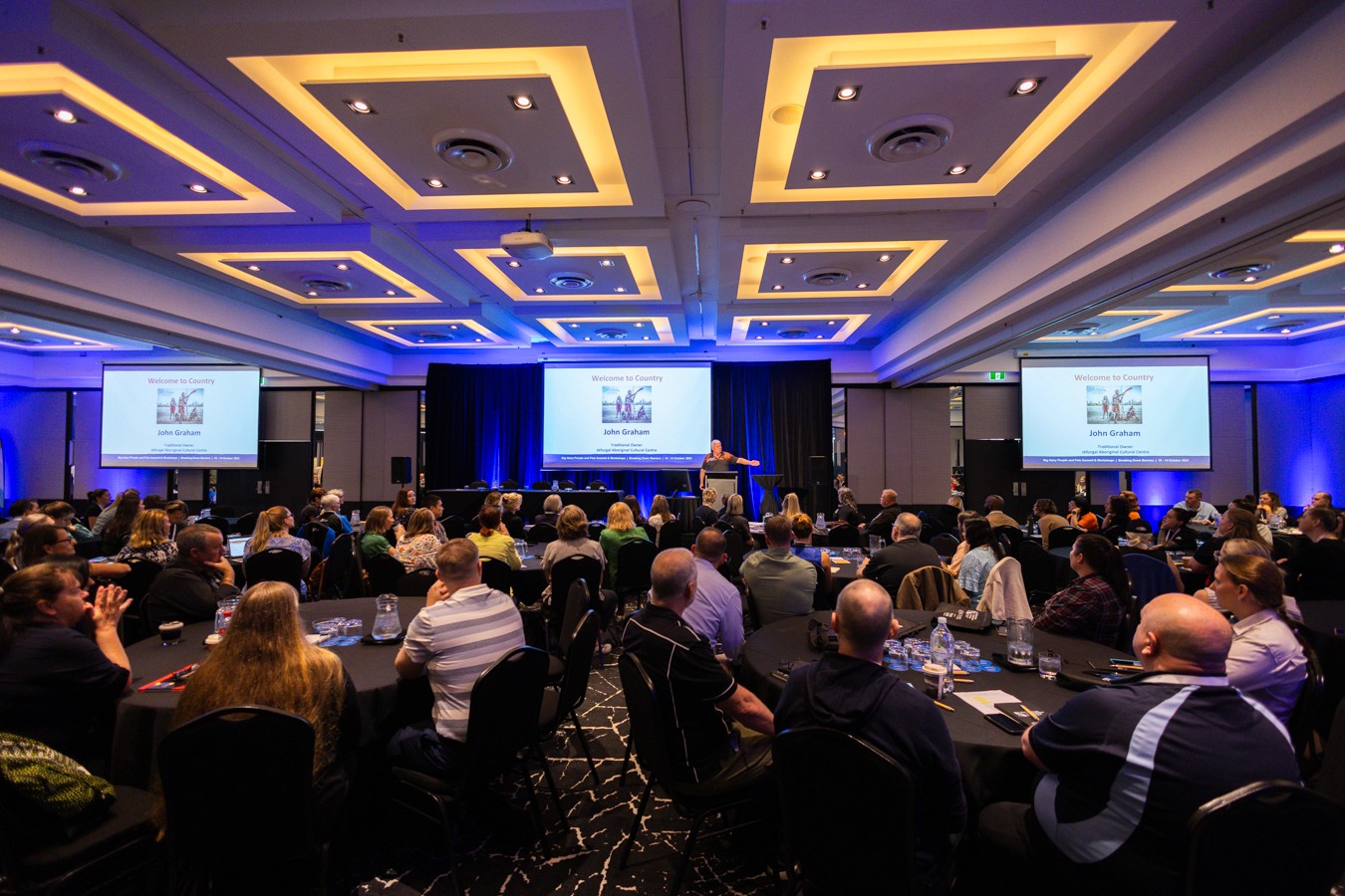Conference room full of people sitting at round tables