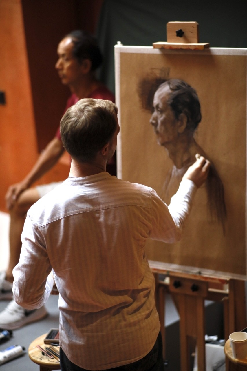 A woman observes framed black-and-white photographs in warm golden light