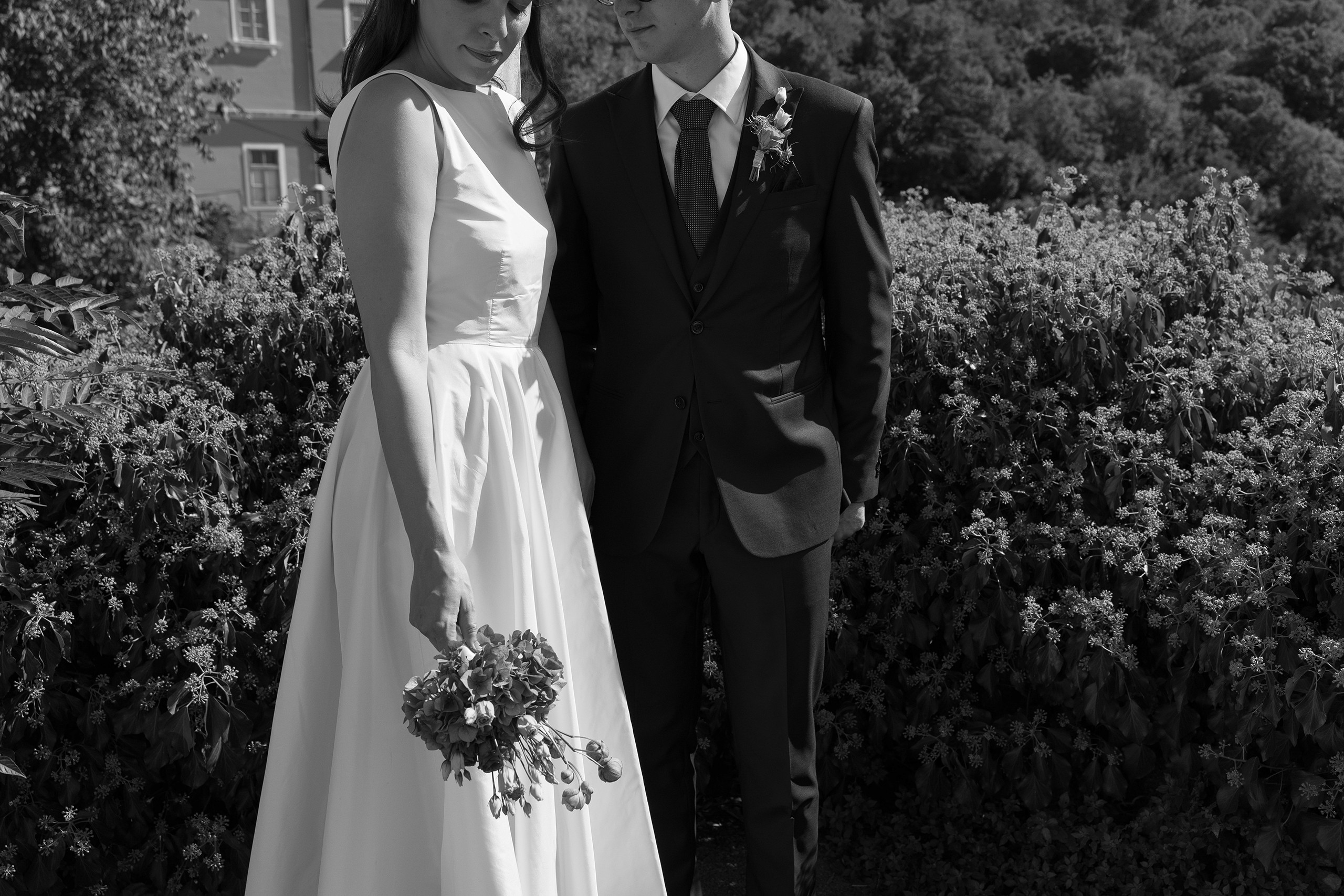 Bride and groom standing on hillside holding hands and bouqet