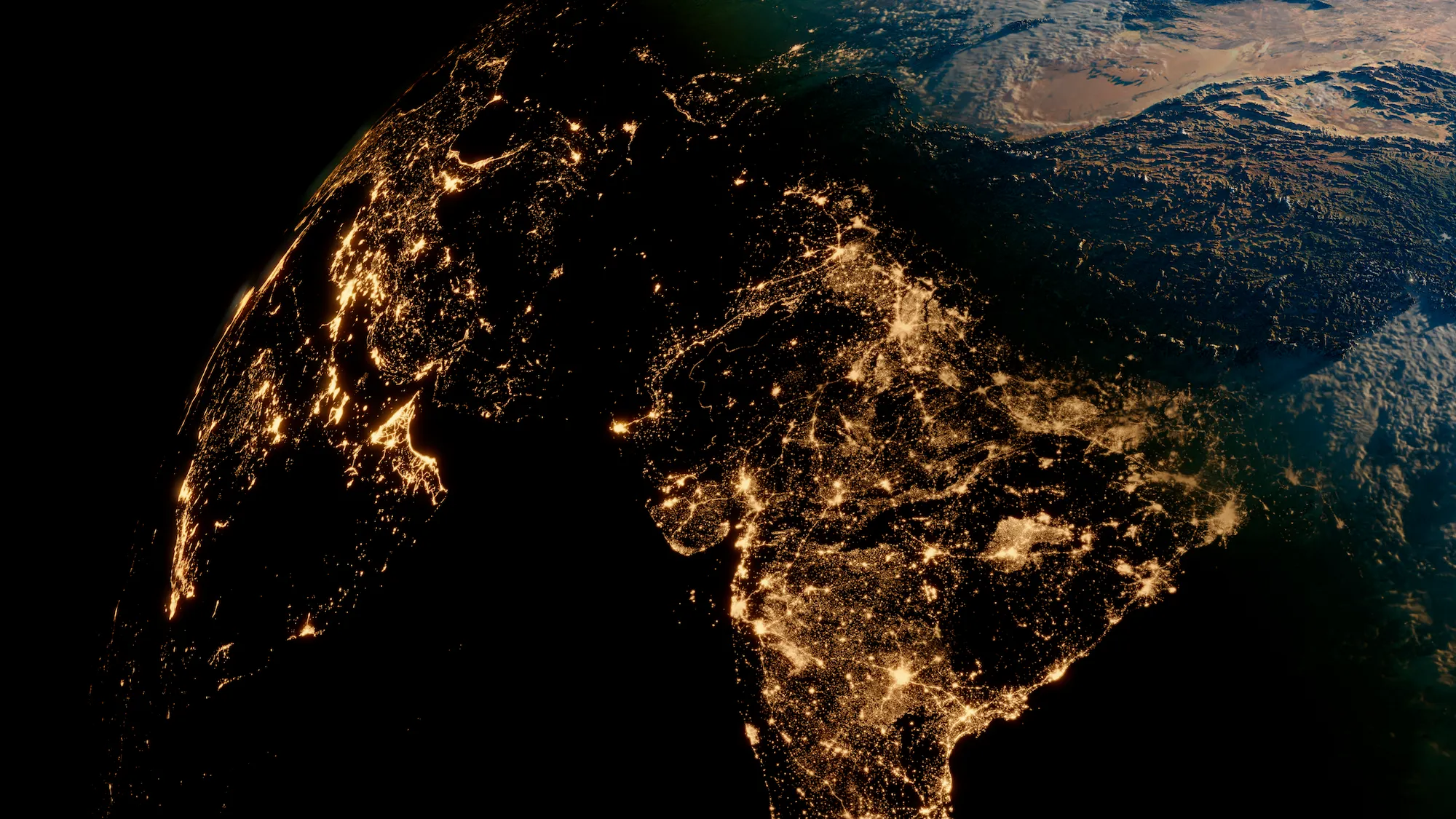 A satellite view of Earth at night, showing illuminated city lights across continents, with a portion of the planet's curve visible.