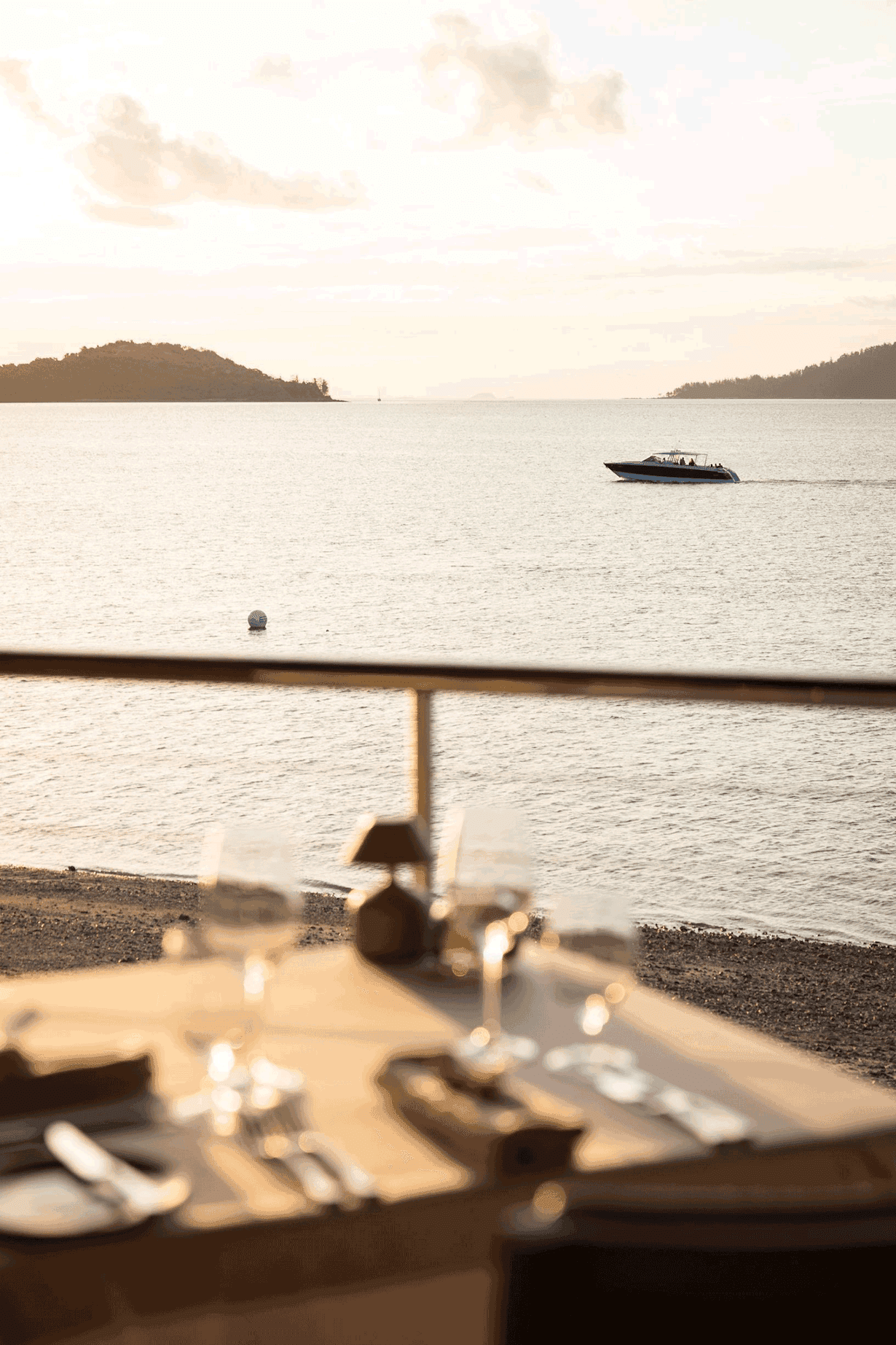 Close-up portrait of a person wearing a gray insulated hooded jacket with the hood up, showing their face framed by the hood against a light background.