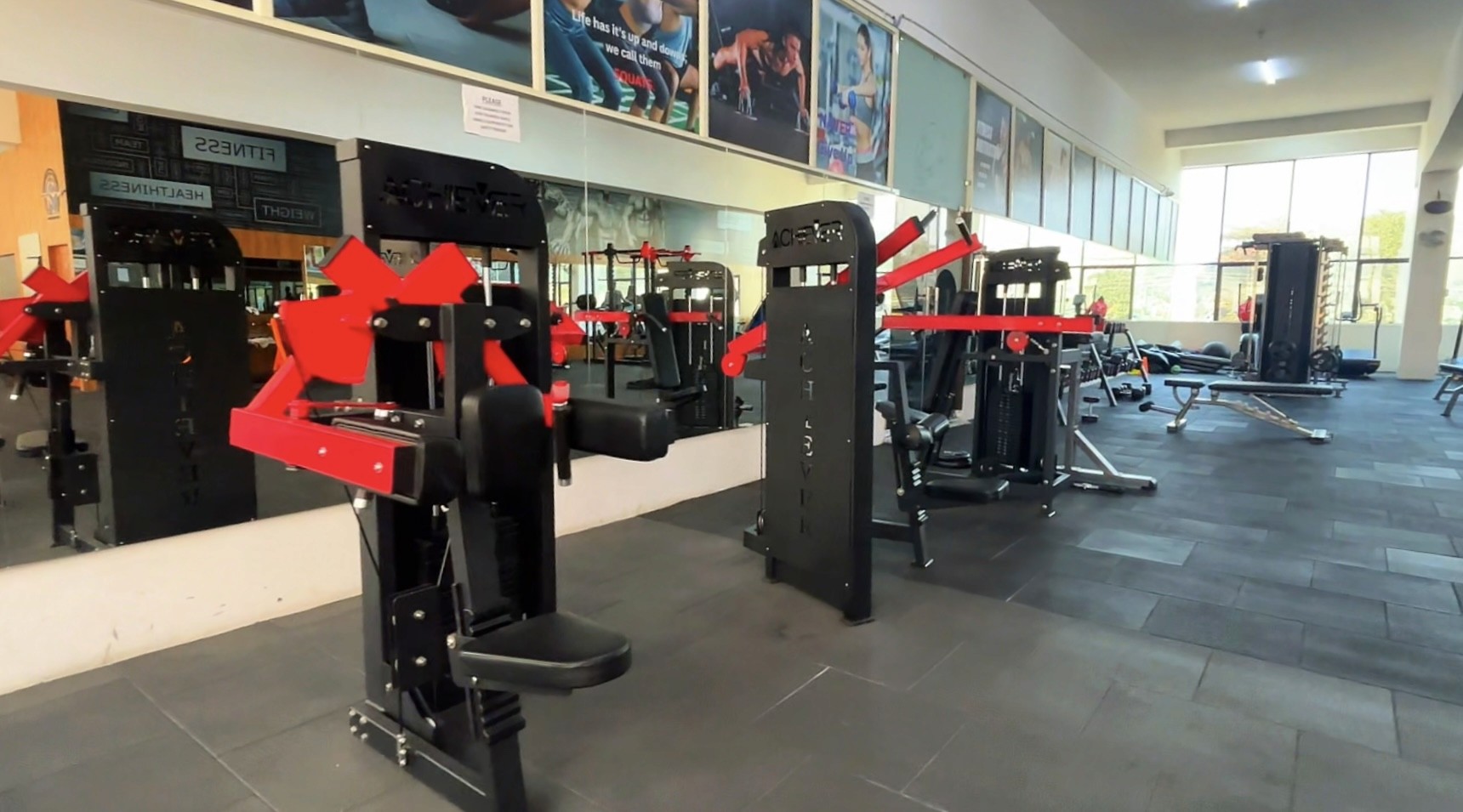Modern glass and wood cabin with a cozy outdoor deck featuring wicker furniture, surrounded by lush green trees and a serene forest setting.