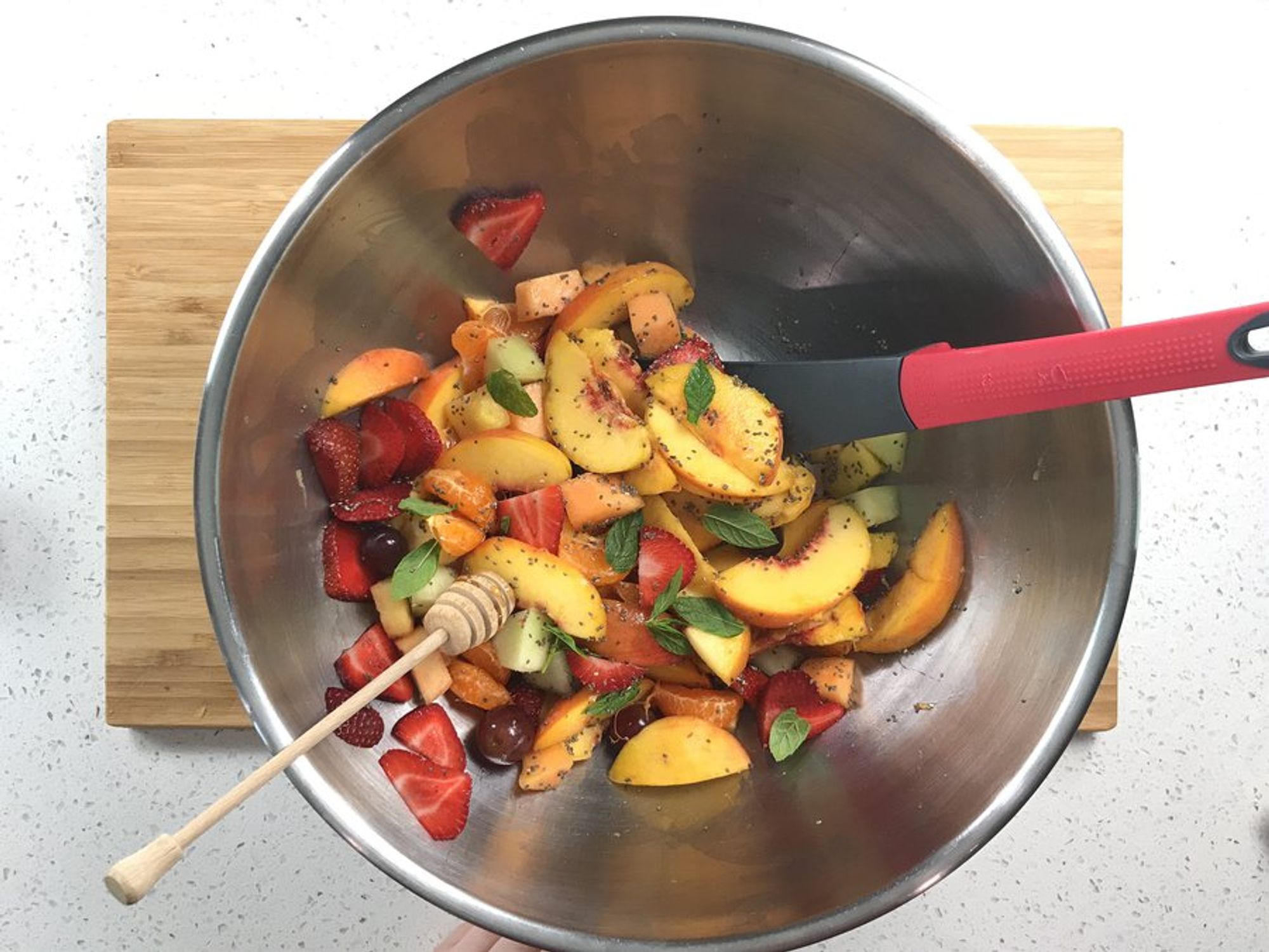fruit ingredients of mint chia salad being tossed in a large bowl