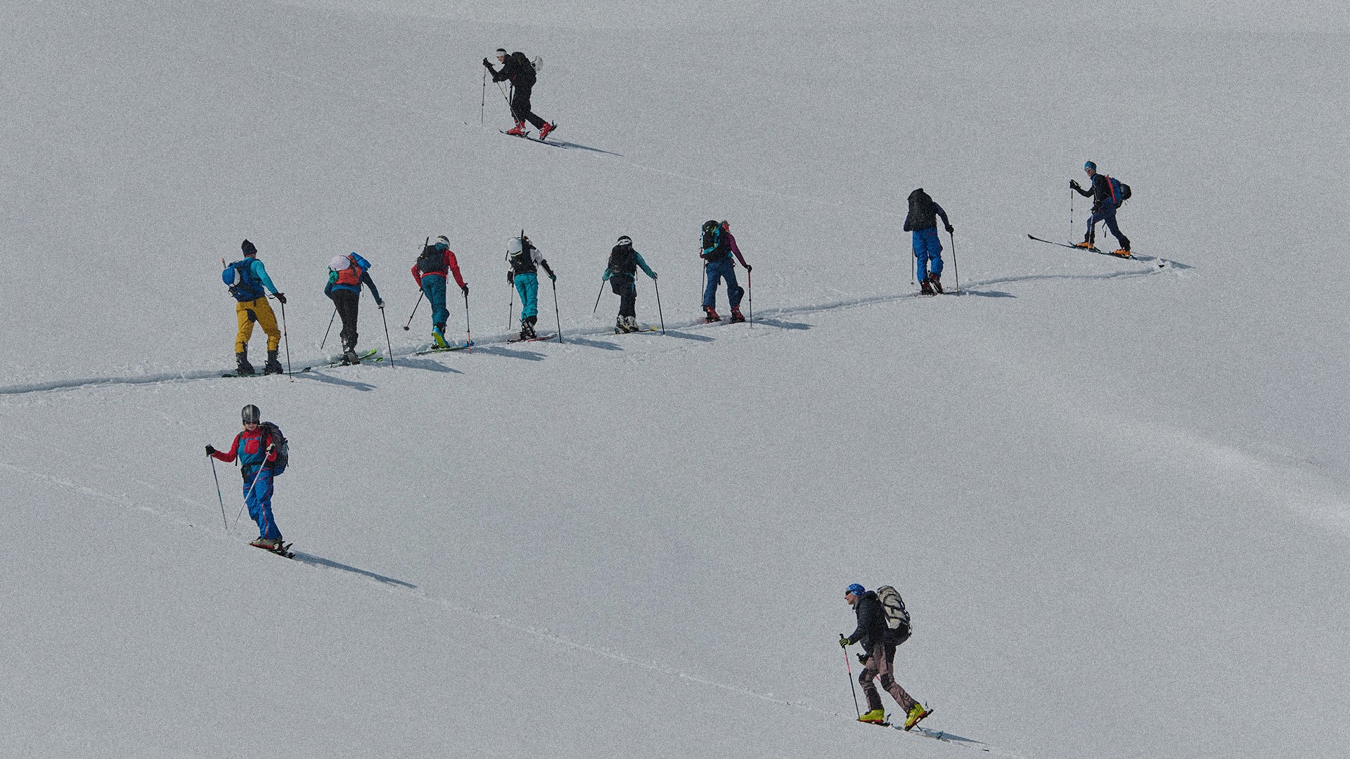 A group of people walking up a ski hill covered in snow.
