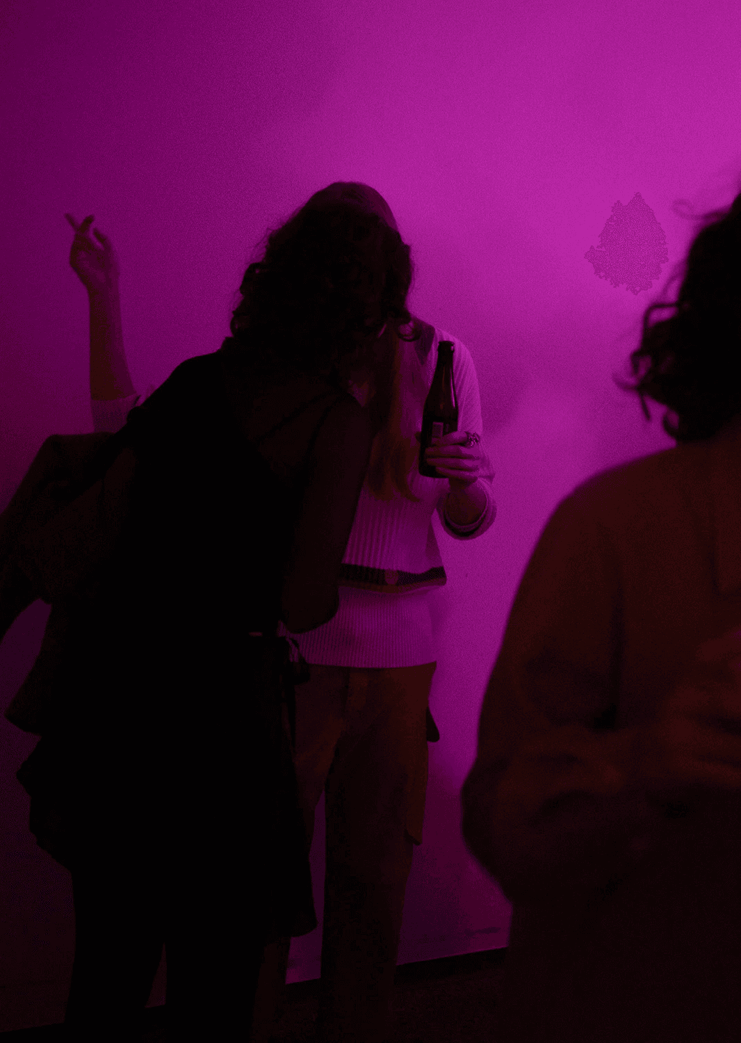 Candid silhouettes of guests enjoying drinks against a saturated pink neon background at the studio housewarming. This atmospheric shot captures the vibrant energy of the event, showcasing the studio's vibrant internal culture and its connection to the local creative scene.