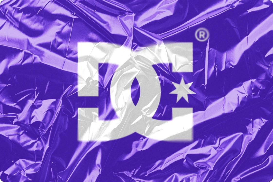 White DC Shoes logo with star and registered trademark symbol centered on crumpled, reflective purple foil, creating a bold, energetic look.