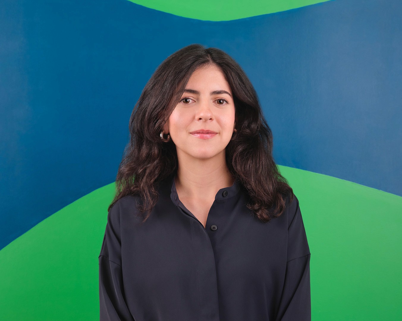 Portrait of Maria José Aria standing in front of a colourful mural