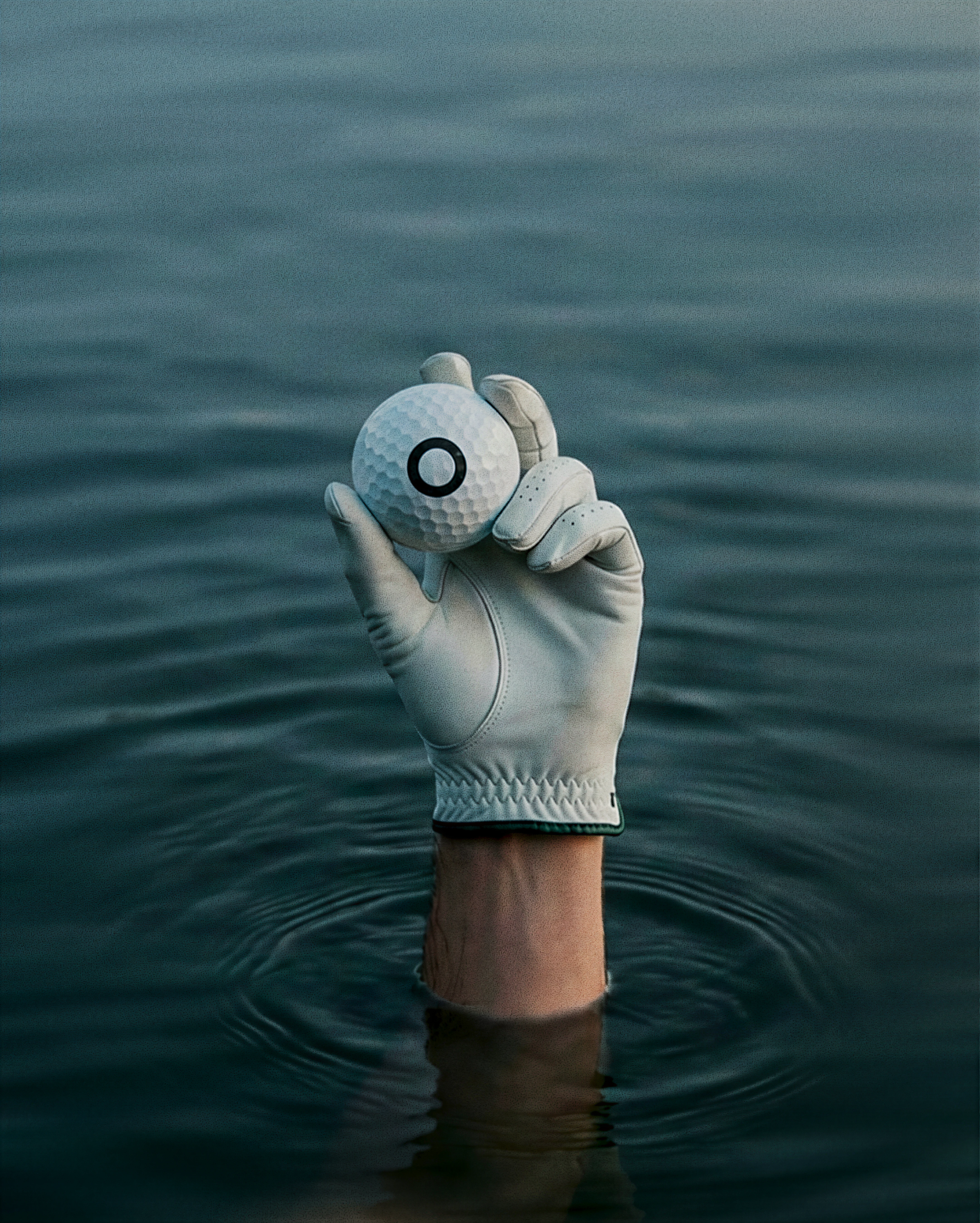 Hand with golf ball under water