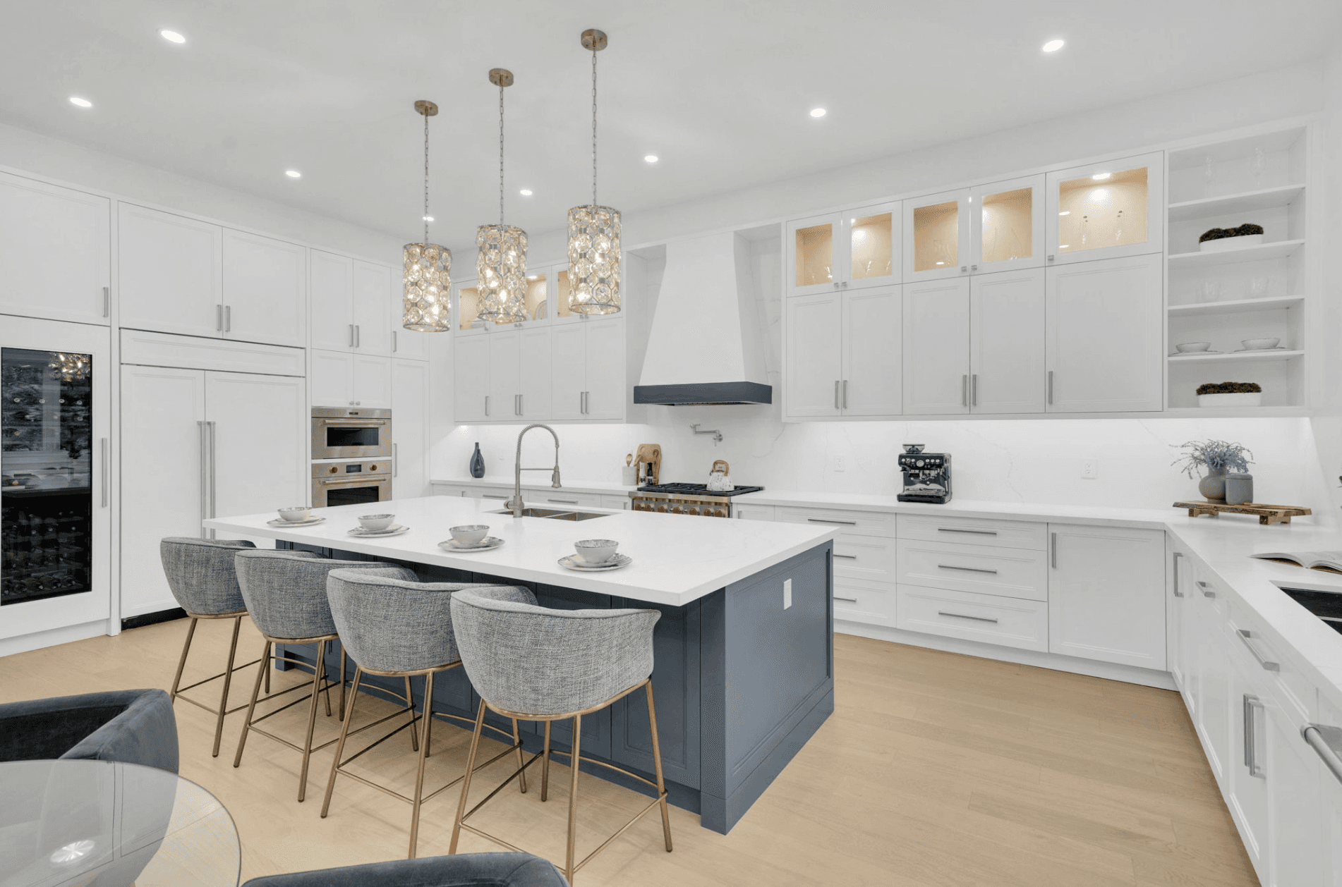Modern kitchen with a wooden dining table, white chairs, and a hanging light fixture above.