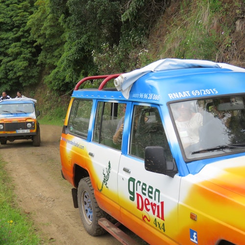 مركبتان دفع رباعي على طريق ترابي، إحداهما تحمل العلامة التجارية "Green Devil 4x4" محاطة بالخضرة والأشجار. أشخاص مرئيين في المركبات.