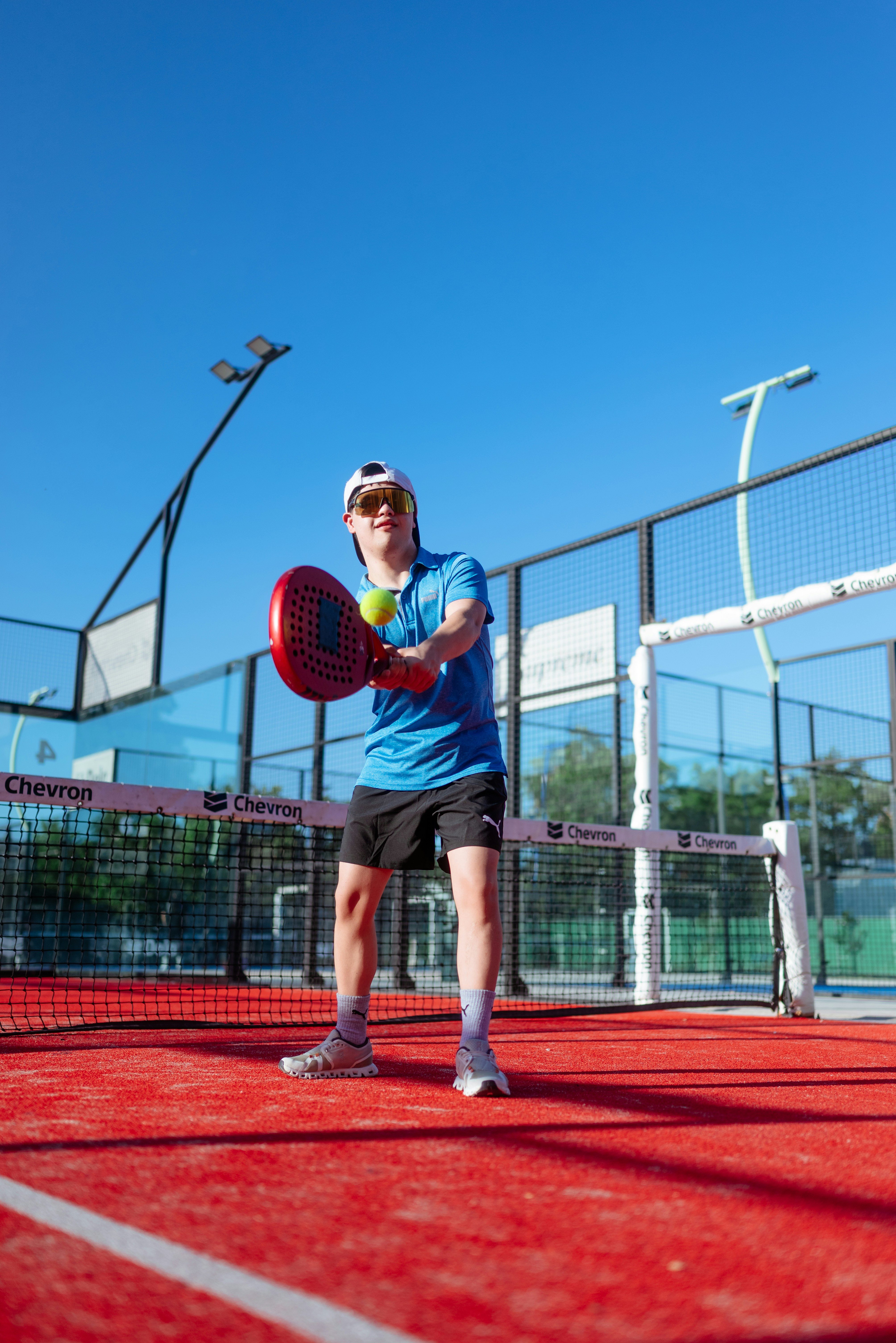 A man is playing padel on a sunny day.
