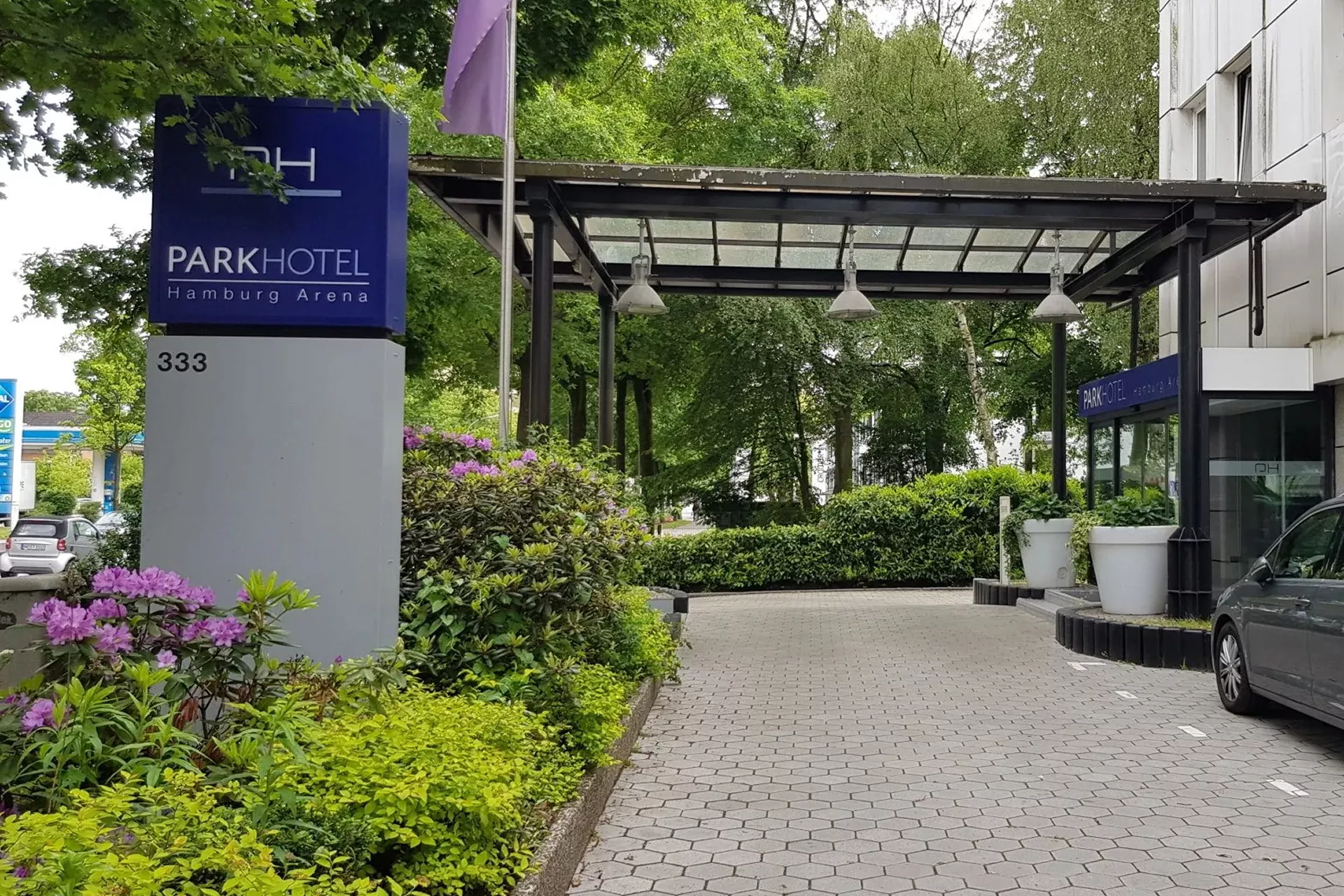 Der Eingangsbereich des Hotels von AUßen mit einer Auffahrt und einem großen Schild mit dem Namen des Hotels