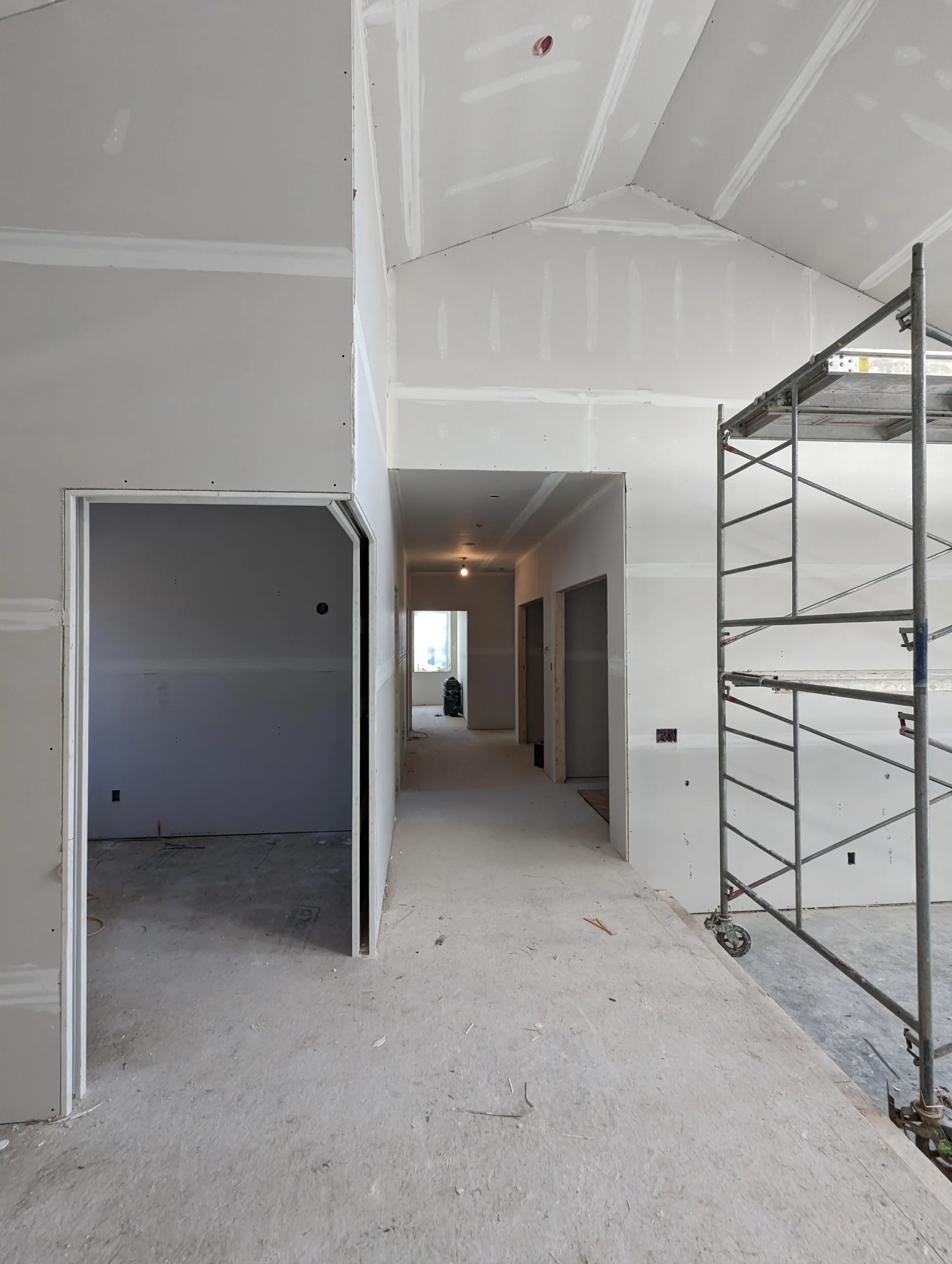 Modern two-story home with large glass windows, warmly lit interiors, and a balcony. Surrounded by trees and a manicured lawn at dusk. Cozy ambiance.