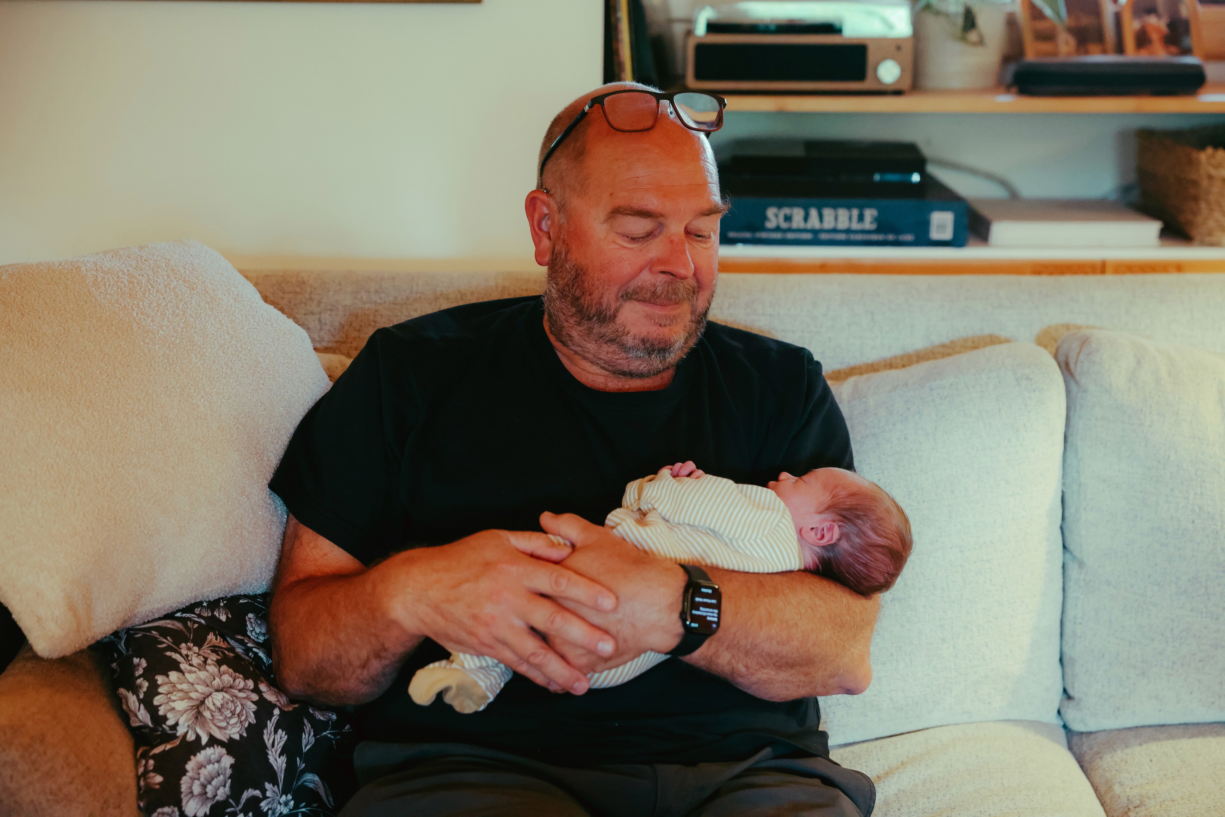 Grandfather on the sofa holding his newborn grandson