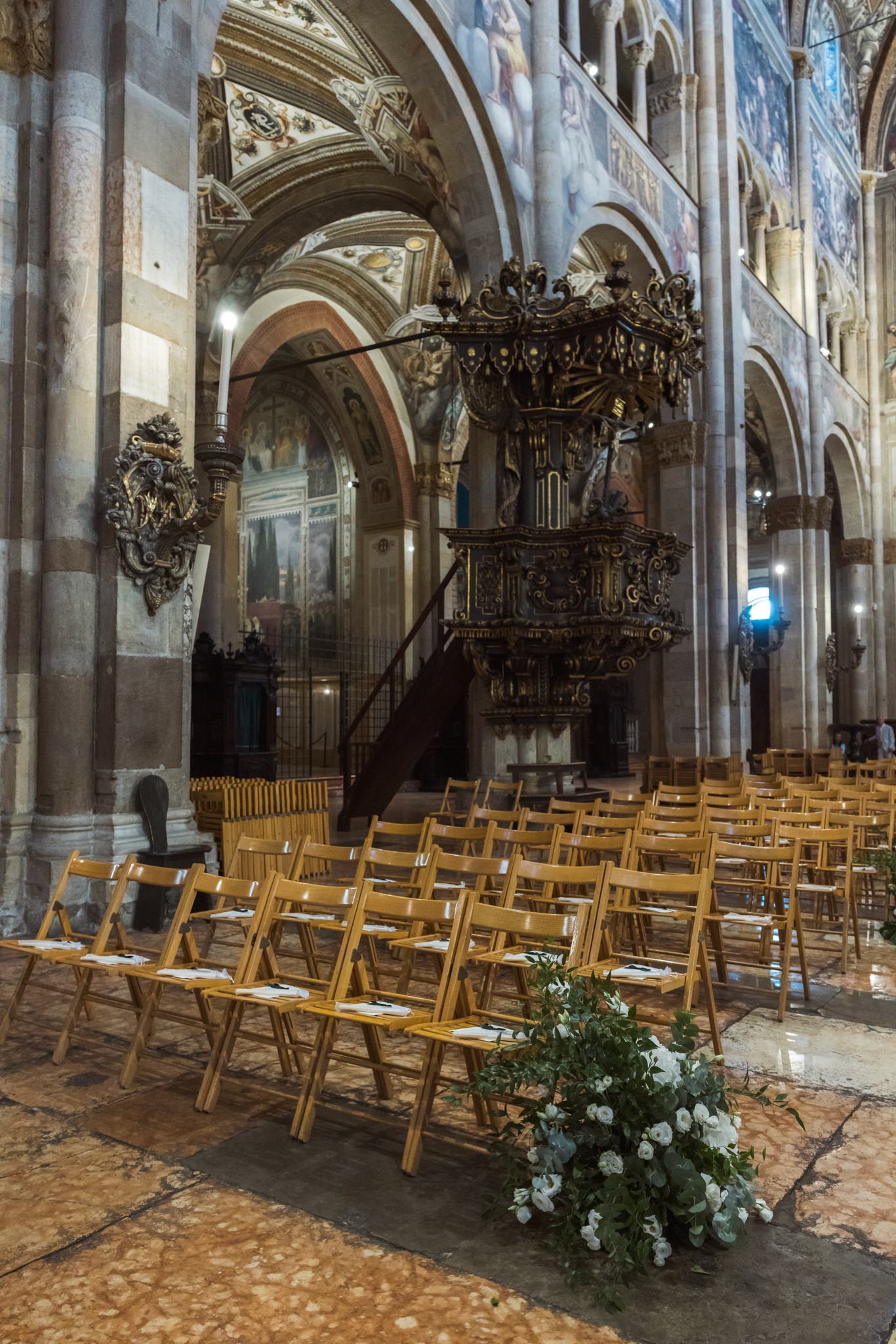 Navata della chiesa barocca con sedie dorate disposte per la cerimonia, organo e decorazioni floreali bianche