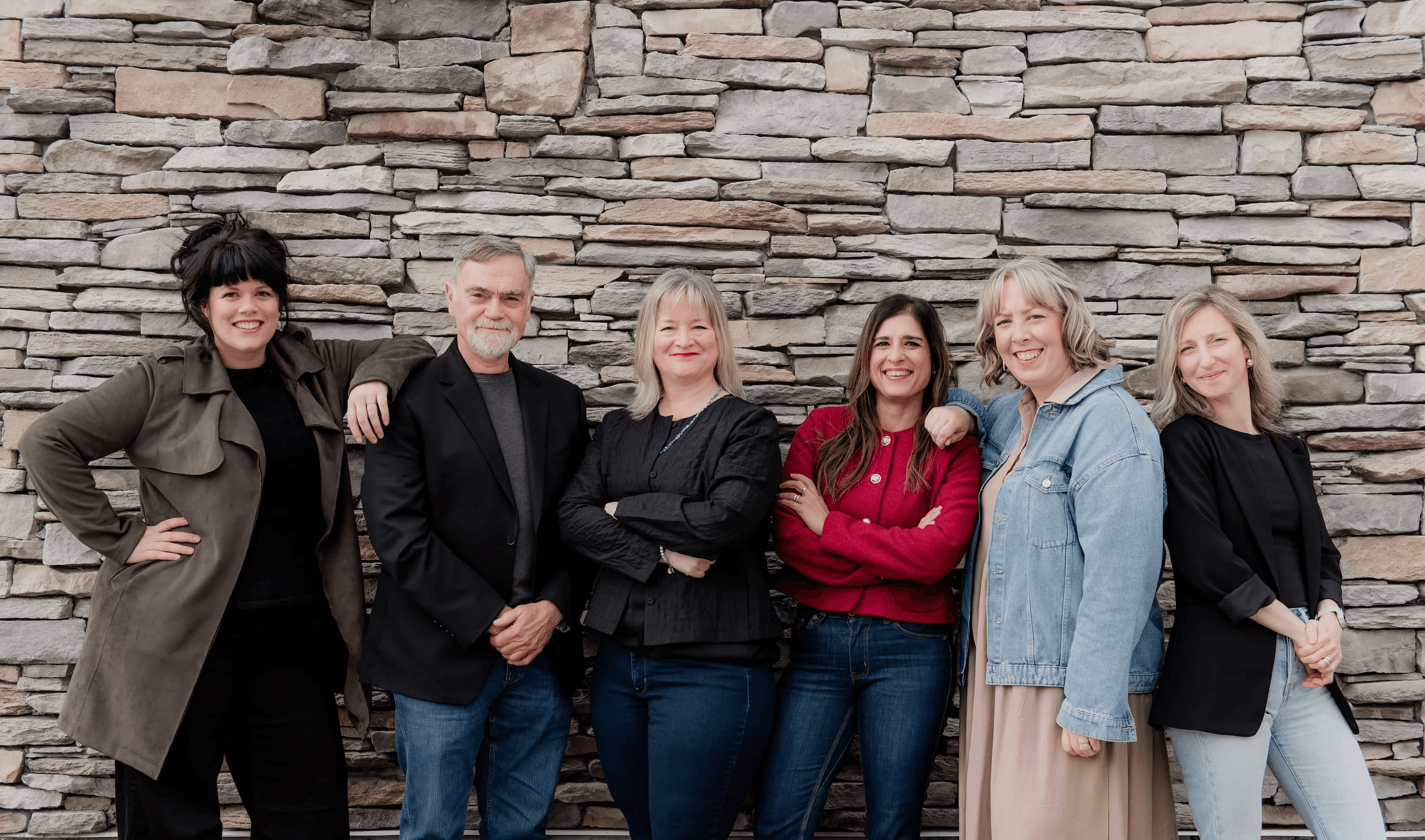 Lantern HR & Leadership team standing together in front of a stone wall, smiling and posing confidently.