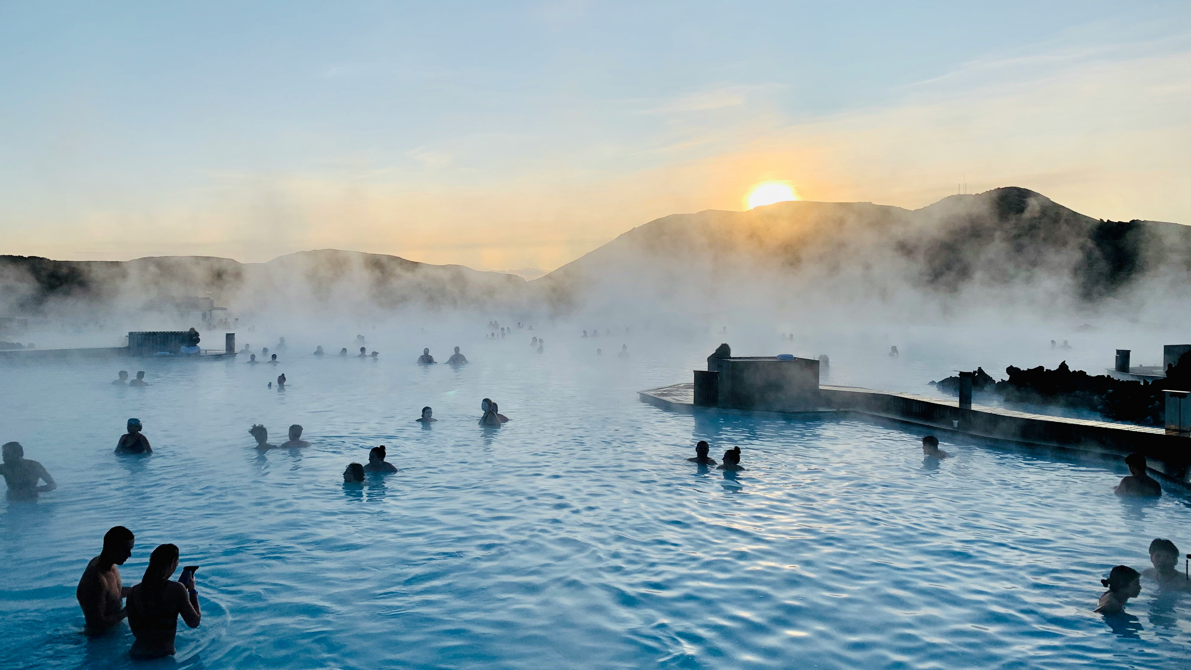 People soaking in the Blue Lagoon in Iceland as the sun sets.