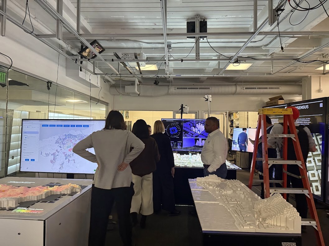 Modern home office setup with a monitor, ergonomic chair, keyboard, and indoor plants near a window with blinds.