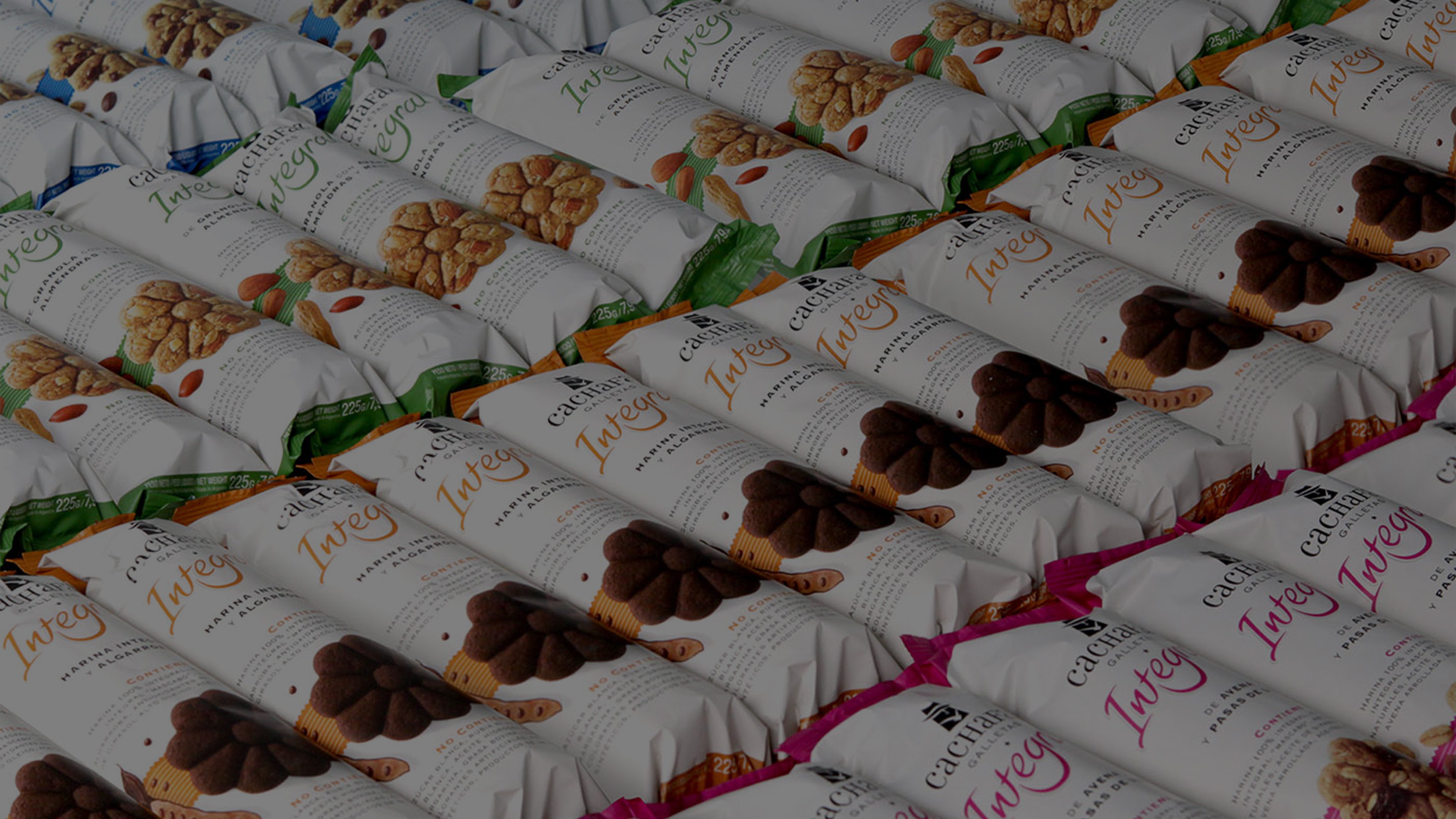 Filas de galletas empaquetadas están organizadas ordenadamente. Los paquetes son blancos con imágenes de galletas, etiquetados en colores vibrantes que indican diferentes sabores.