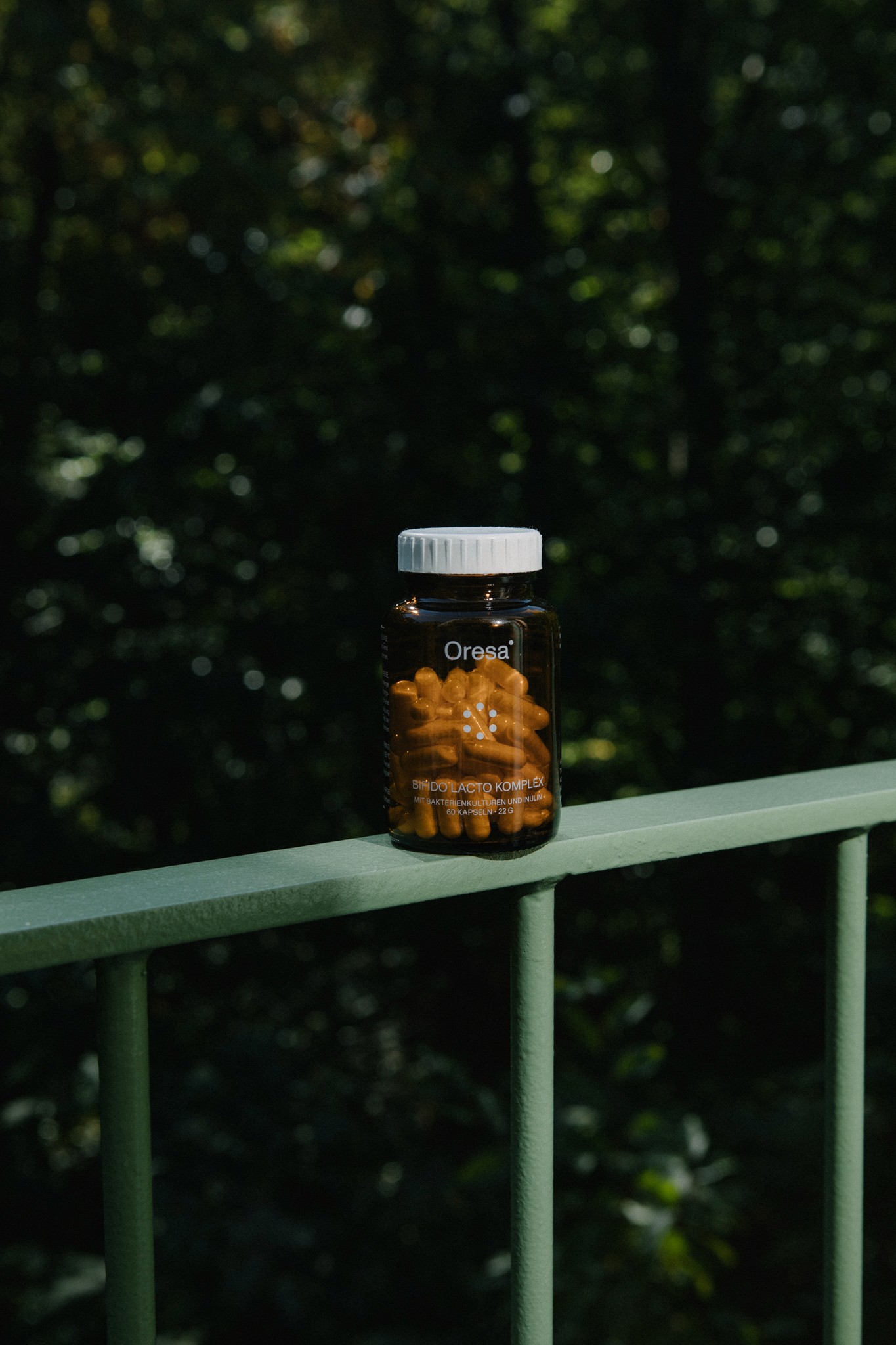 Oresa Bifido Lacto Komplex Kapseln in Glasflasche auf Geländer im Grünen