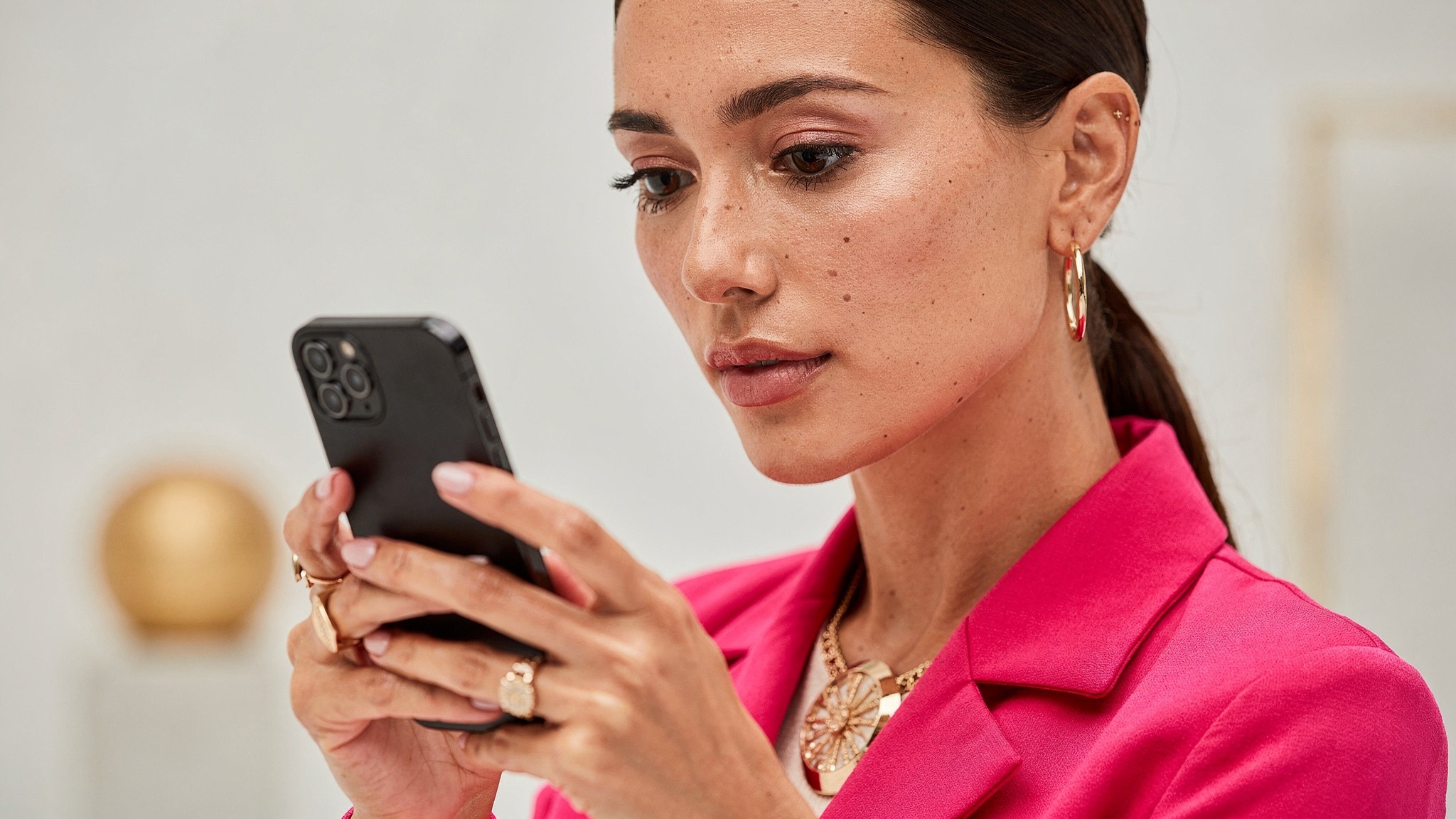 Adult woman creator reviewing video analytics on her phone with a focused expression