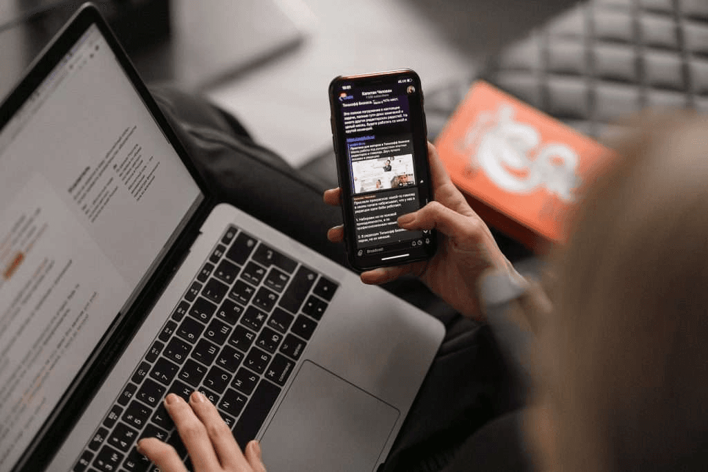 Person using a laptop and a phone at the same time.