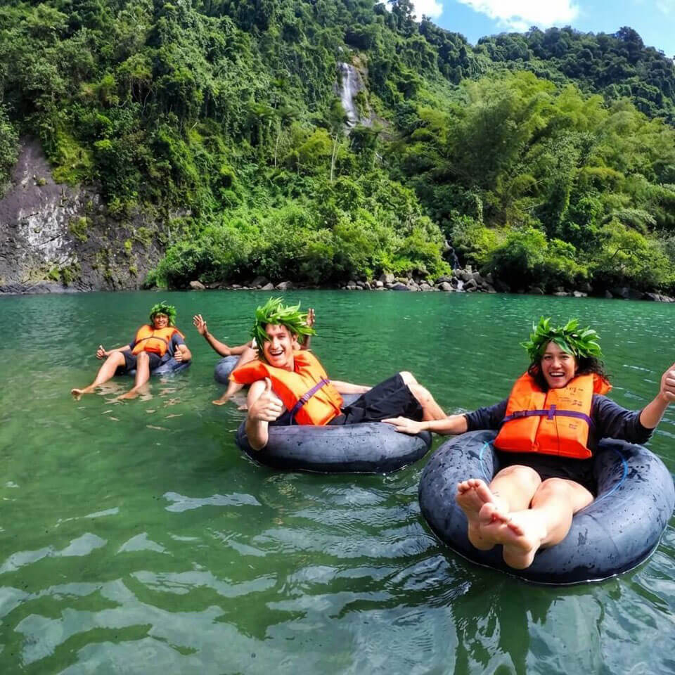 A group of ffriends in a yellow kayak wearing life jackets have just returned looking happy after a riverside cruise