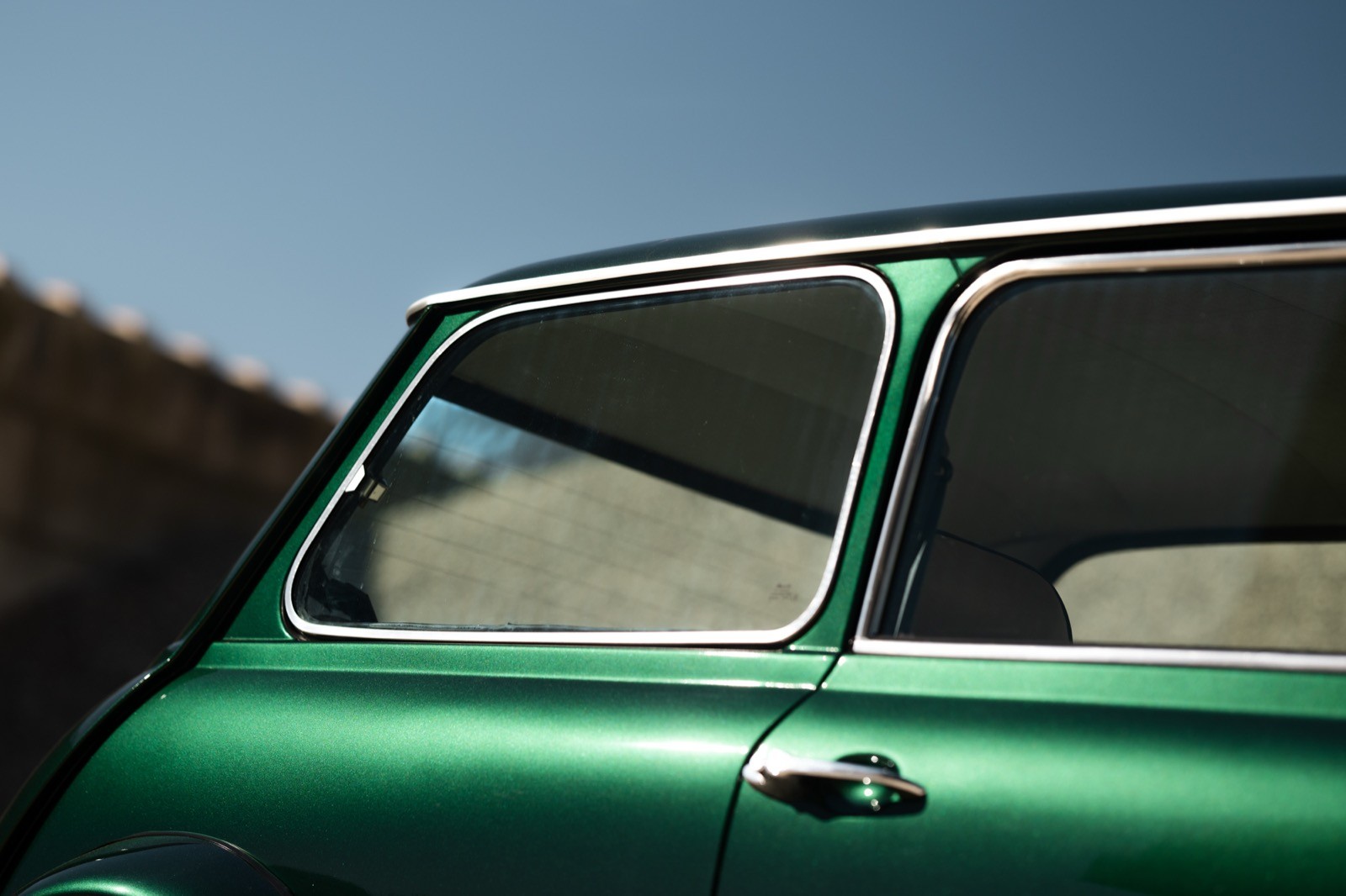 Close-up of a classic car's front, featuring round headlights and a sunset backdrop.