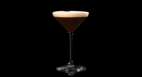 A closeup of an Espresso Martini  drink against a dark background.