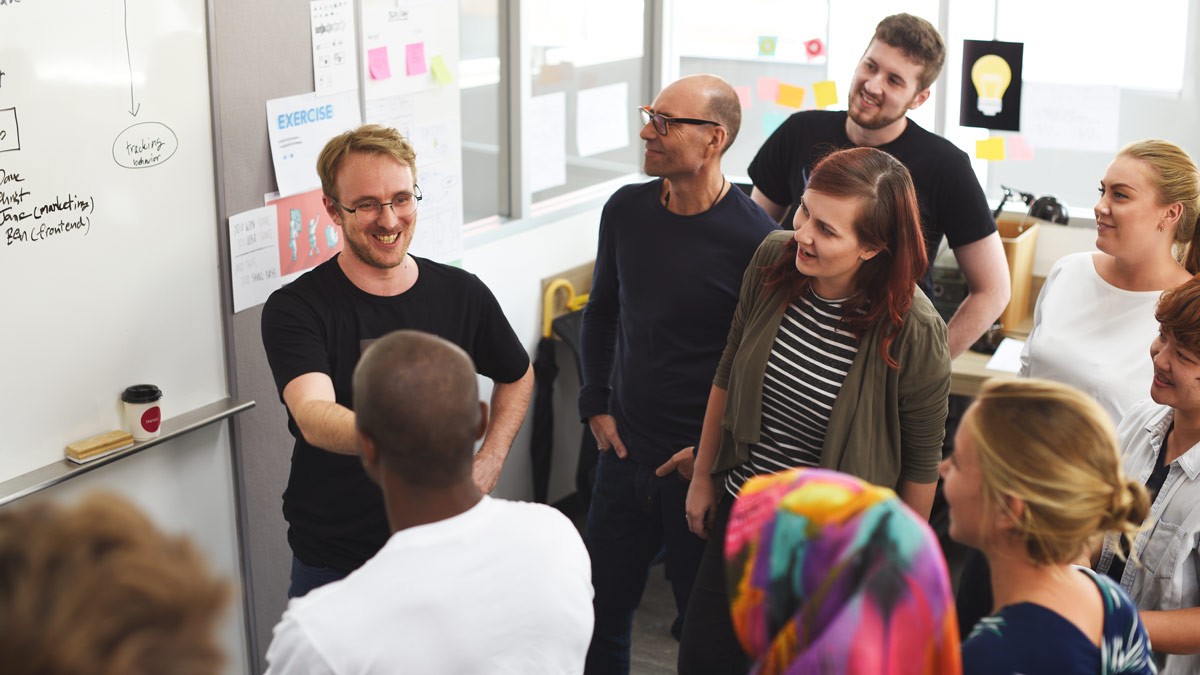 A group of workshop participants standing a front of a whiteboard