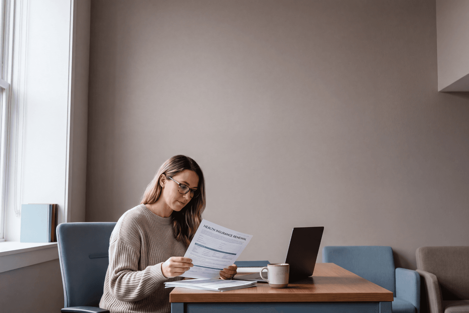 A small business owner going through health plan renewal paperwork at a desk