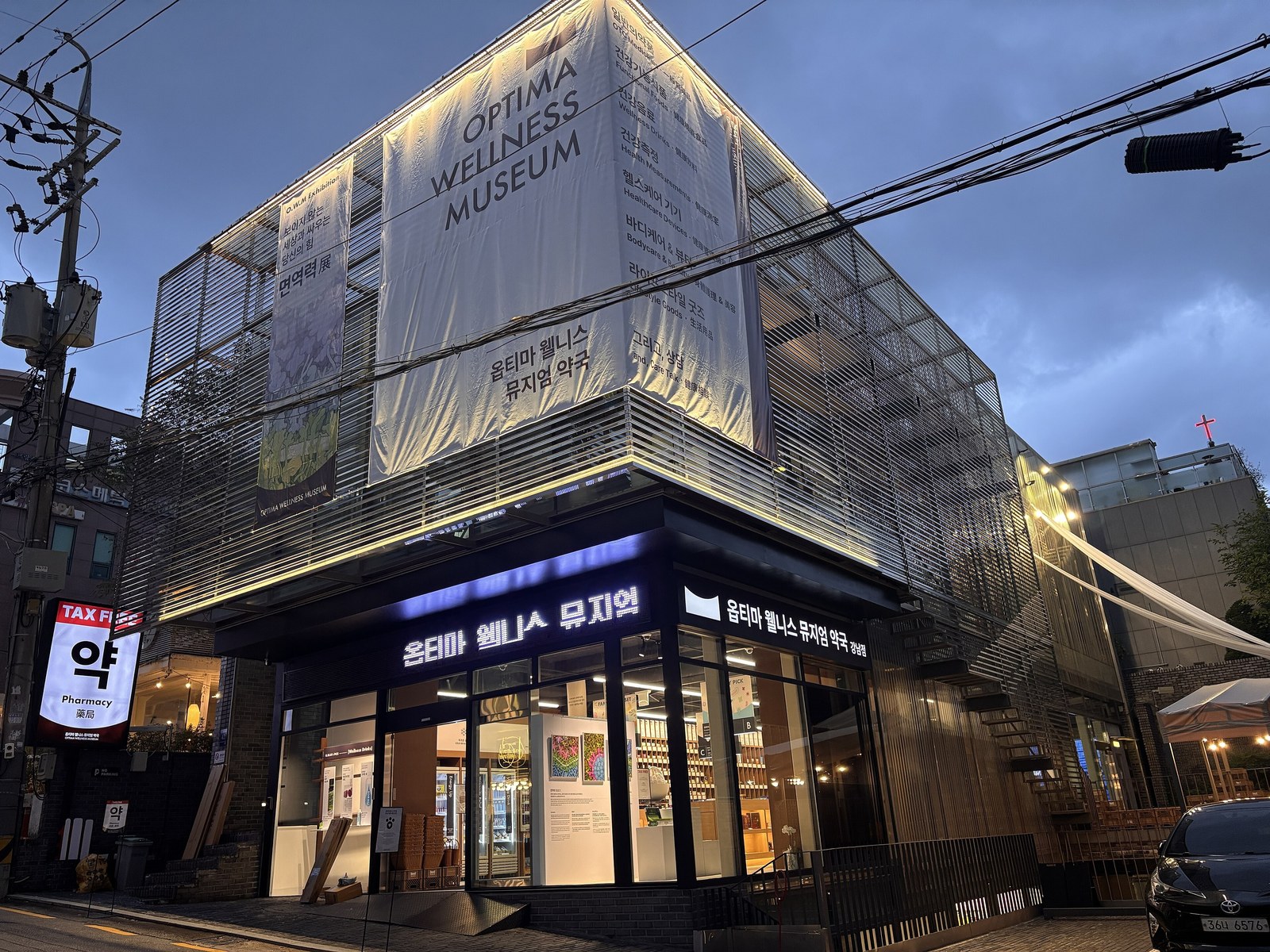 A neighborhood pharmacy in Korea, its signage lit above the entrance.