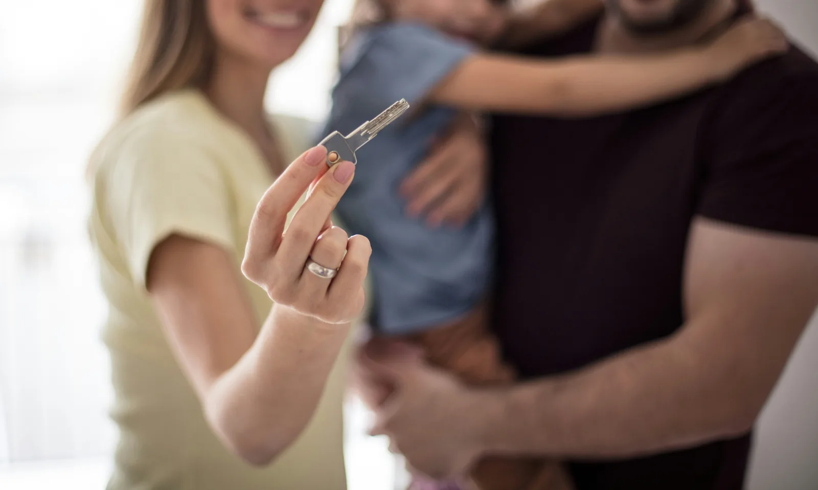 Young family with baby holding house key in focus
