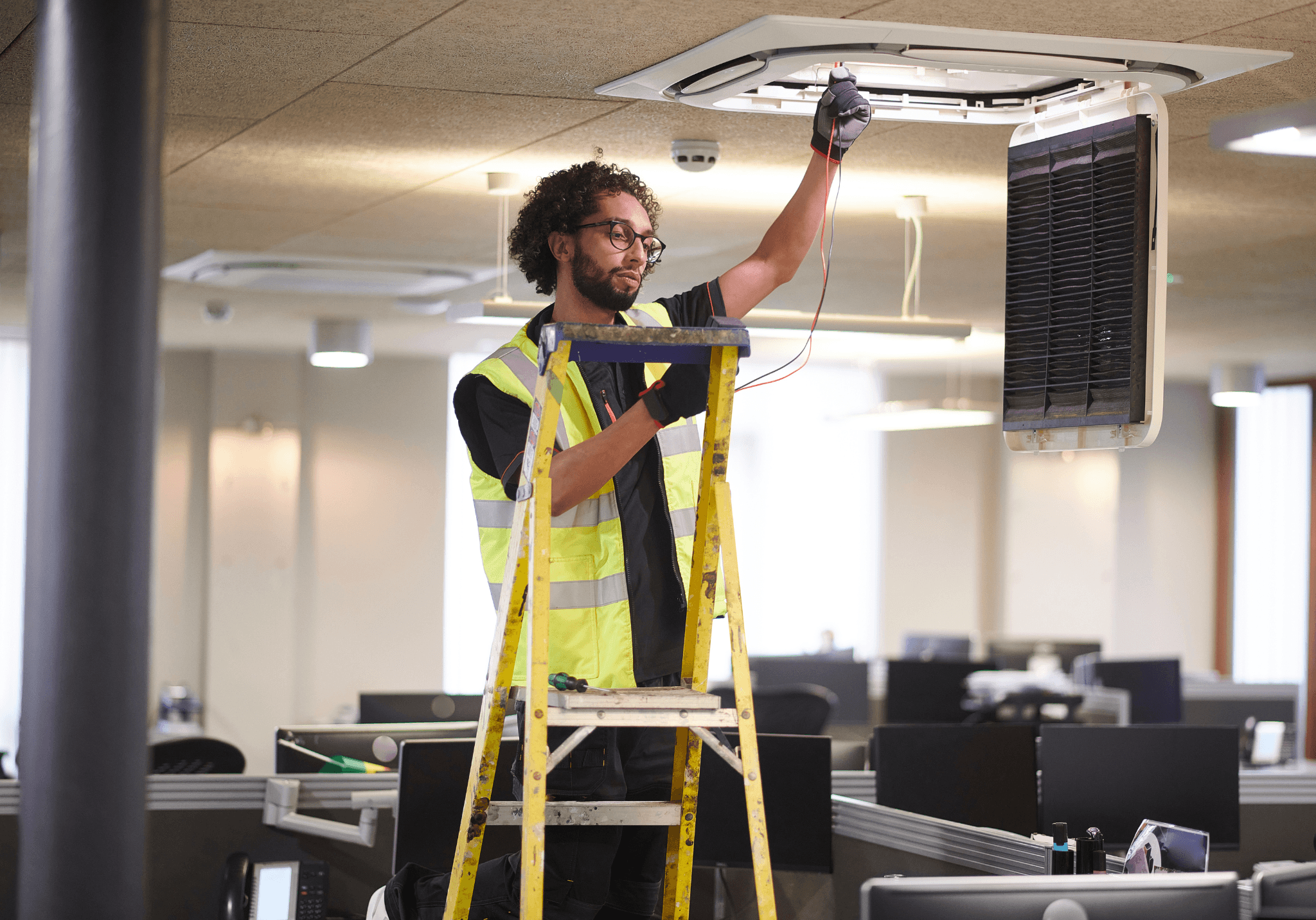 Mechanical and Electrical (M&E) technician installing air conditioning systems in a commercial office.