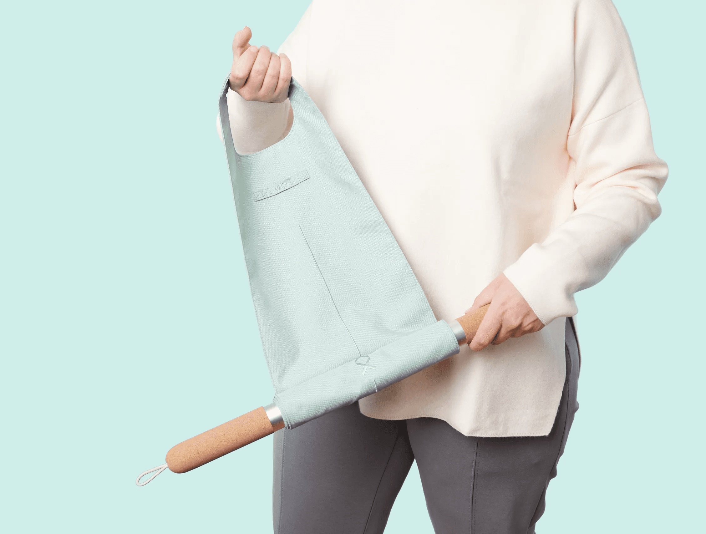 Person holding CastleFlexx by its cork handle and flexible fabric strap